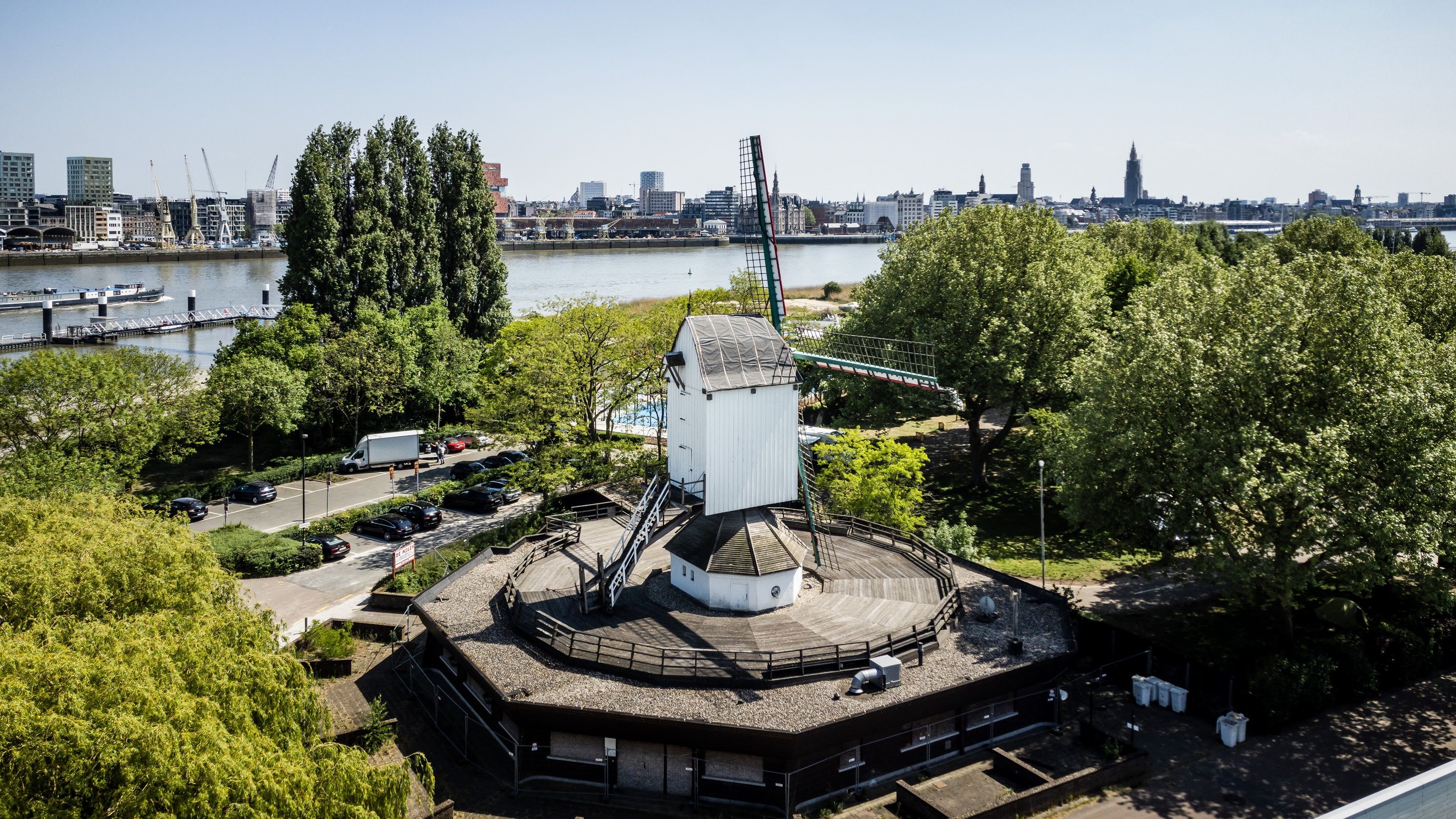 Een witte molen gefotografeerd vanuit de lucht met de Schelde op de achtergrond.