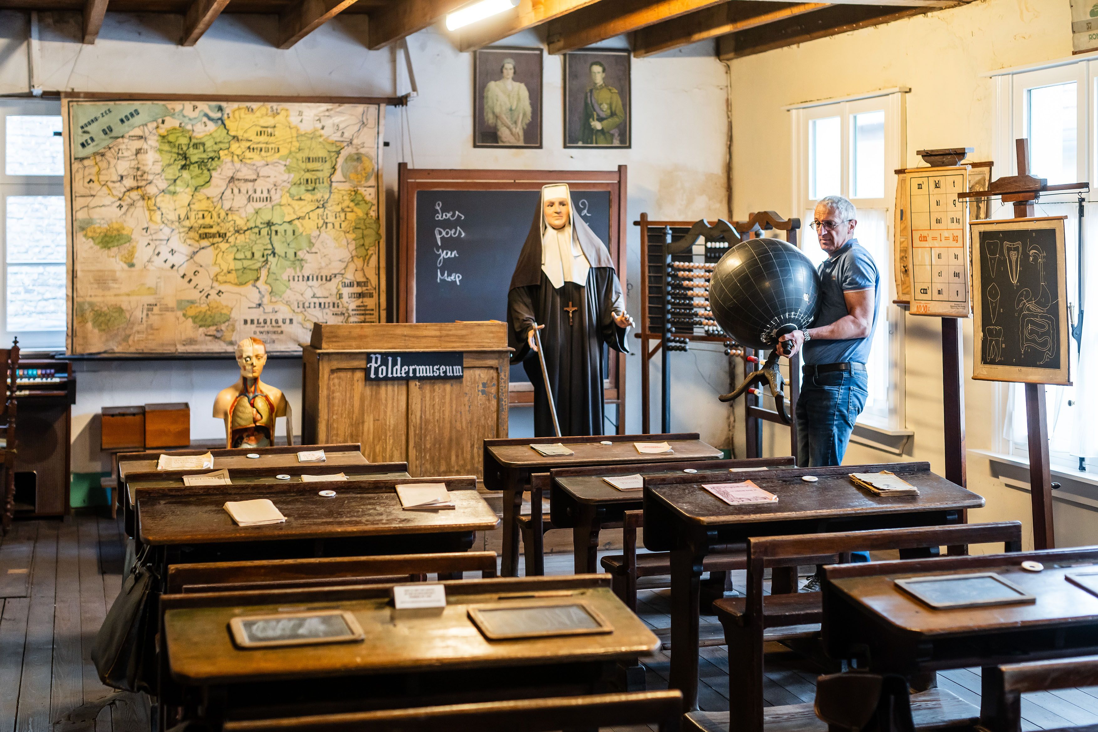 Een vrijwilliger verzet een museumstuk in het oude klasje in het poldermuseum.