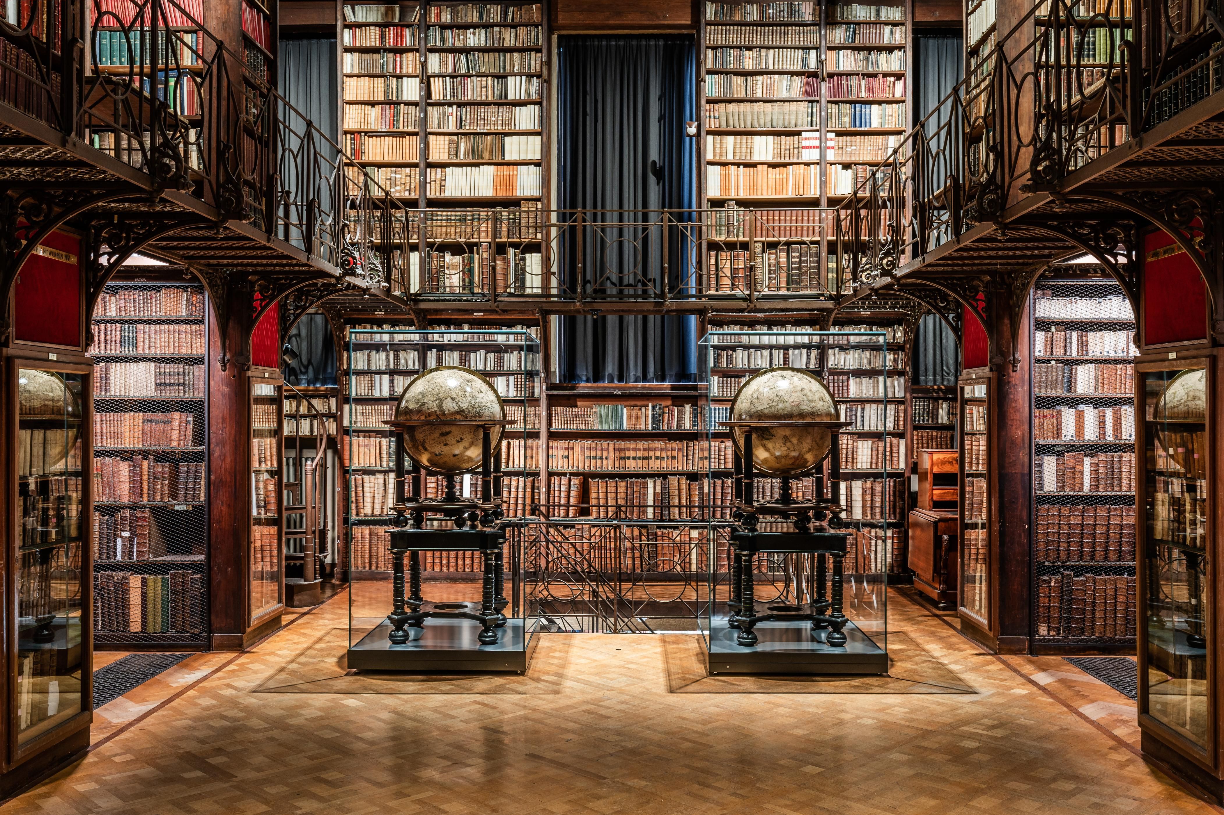 De Nottebohmzaal met 2 grote wereldbollen die in de ruimte staan en boekenkasten tegen elke muur. 