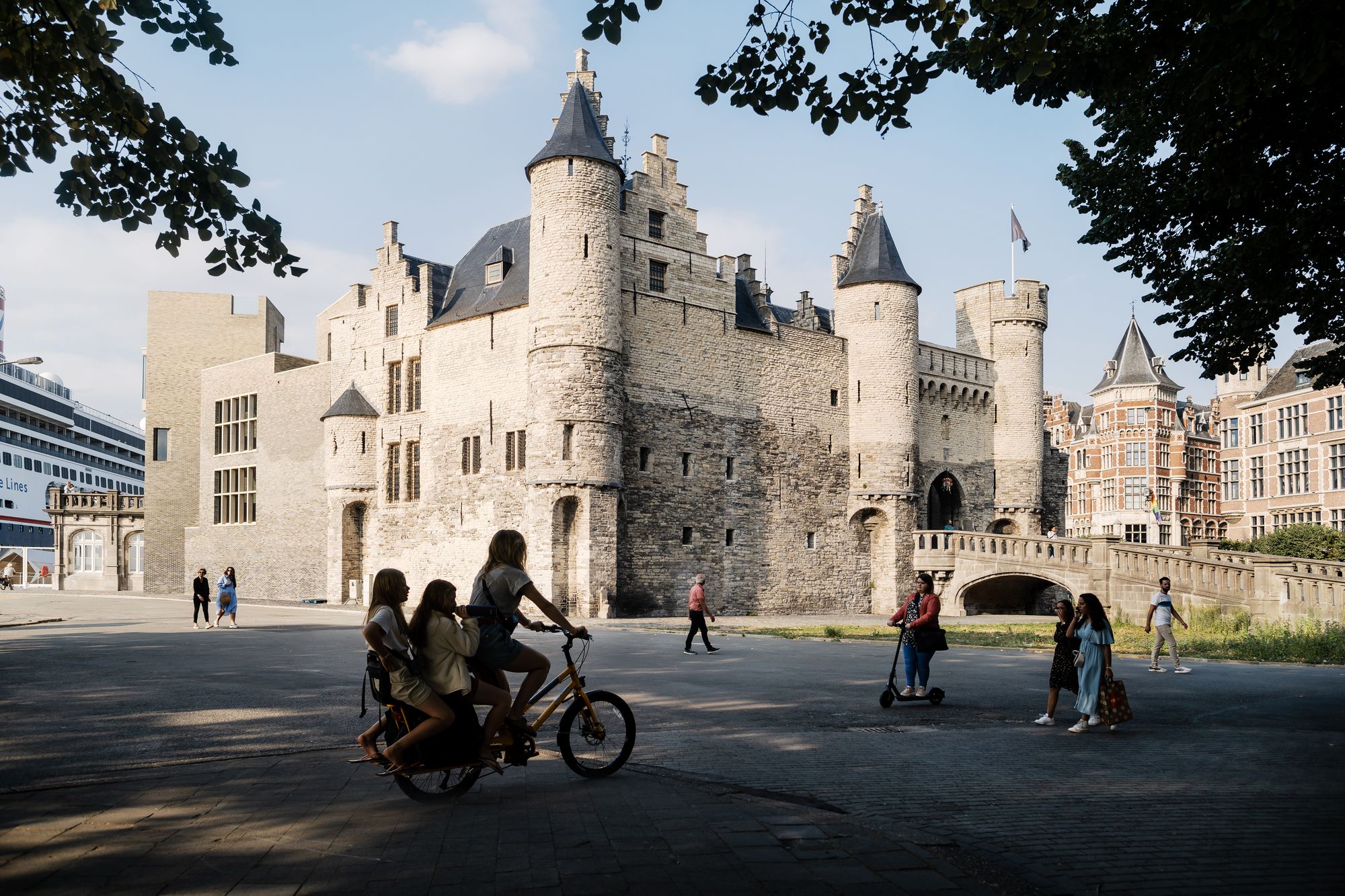 Zicht op het steen vanop het Steenplein met enkele passanten die voorbije fietsen en wandelen.