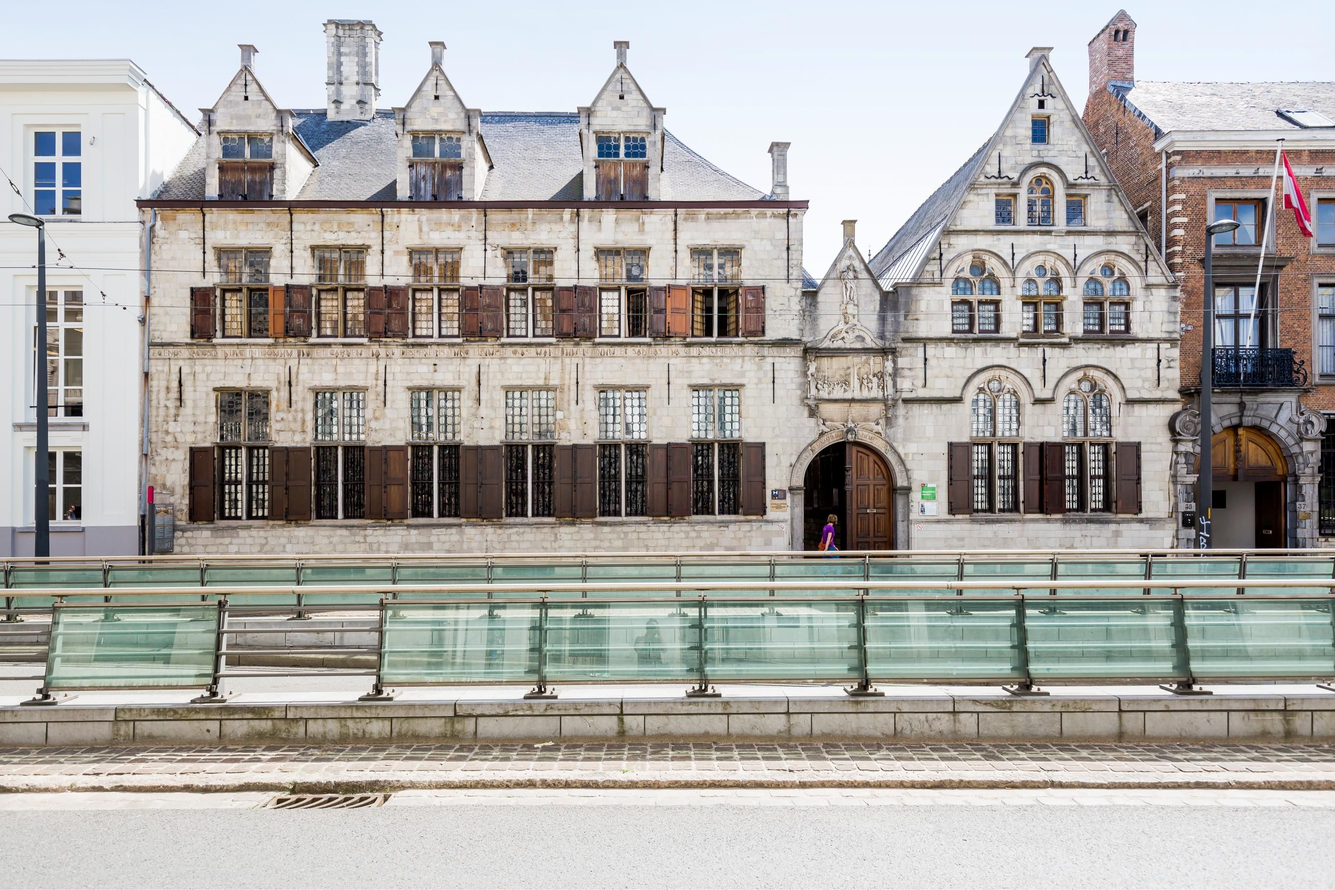 Zicht op de straatgevel van het Maagdenhuis, lichtgekleurde gevel met houten luiken en zwarte leien daken
