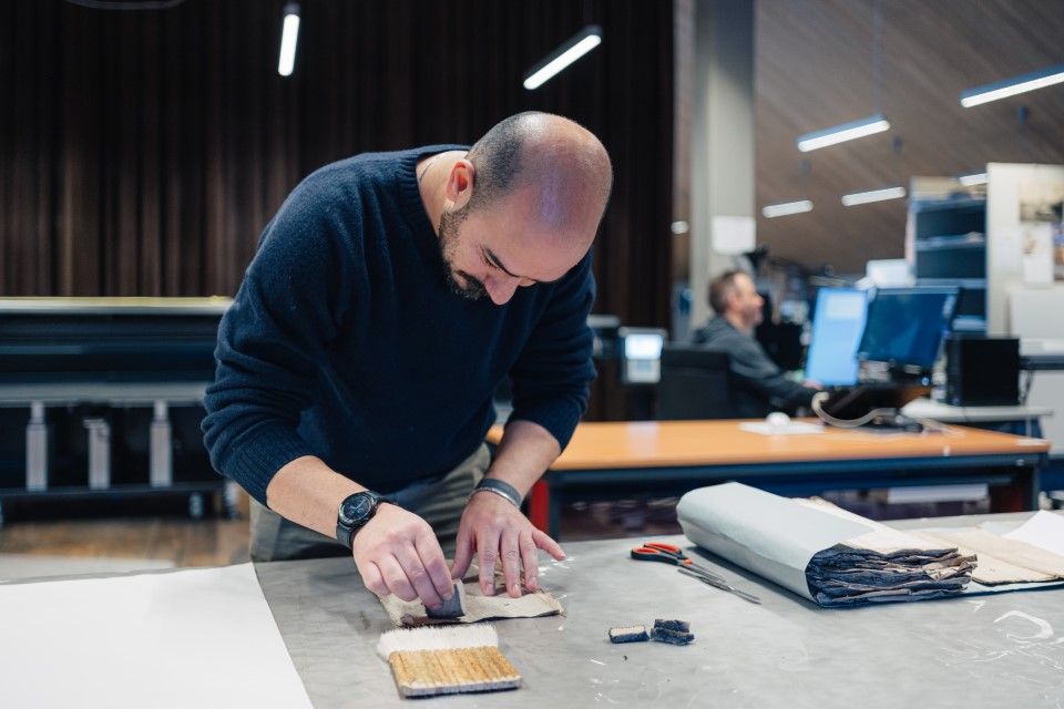 Medewerker onderzoekt archiefstukken op een werkbank.