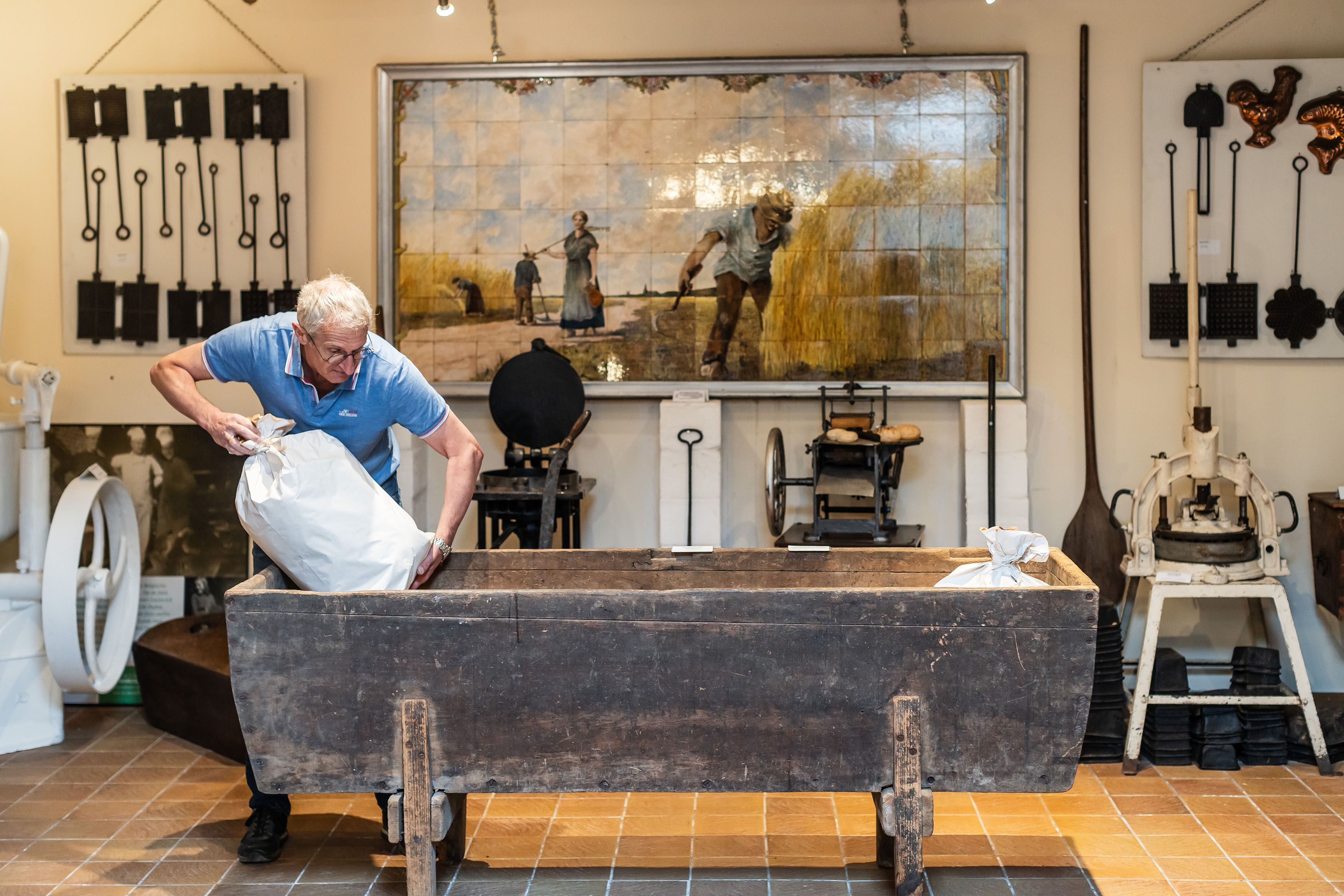 Een vrijwilliger onderhoudt een museumstuk, het is een stuk uit de voormalige beschuitbakkerij die hier vroeger gevestigd was.