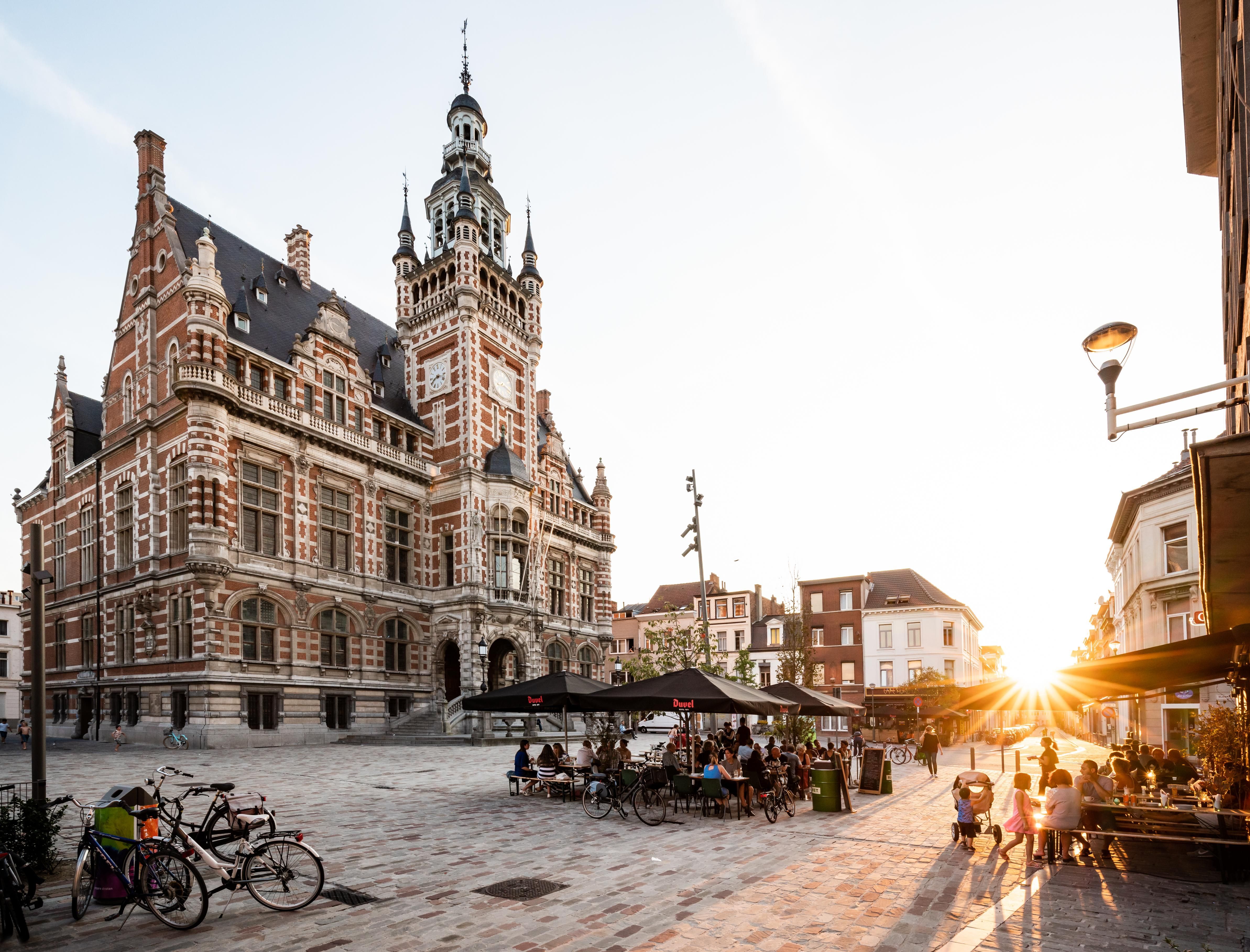 Links het districtshuis van Borgerhout. Rechts in beeld huizen en een caféterras waar de zon op schijnt