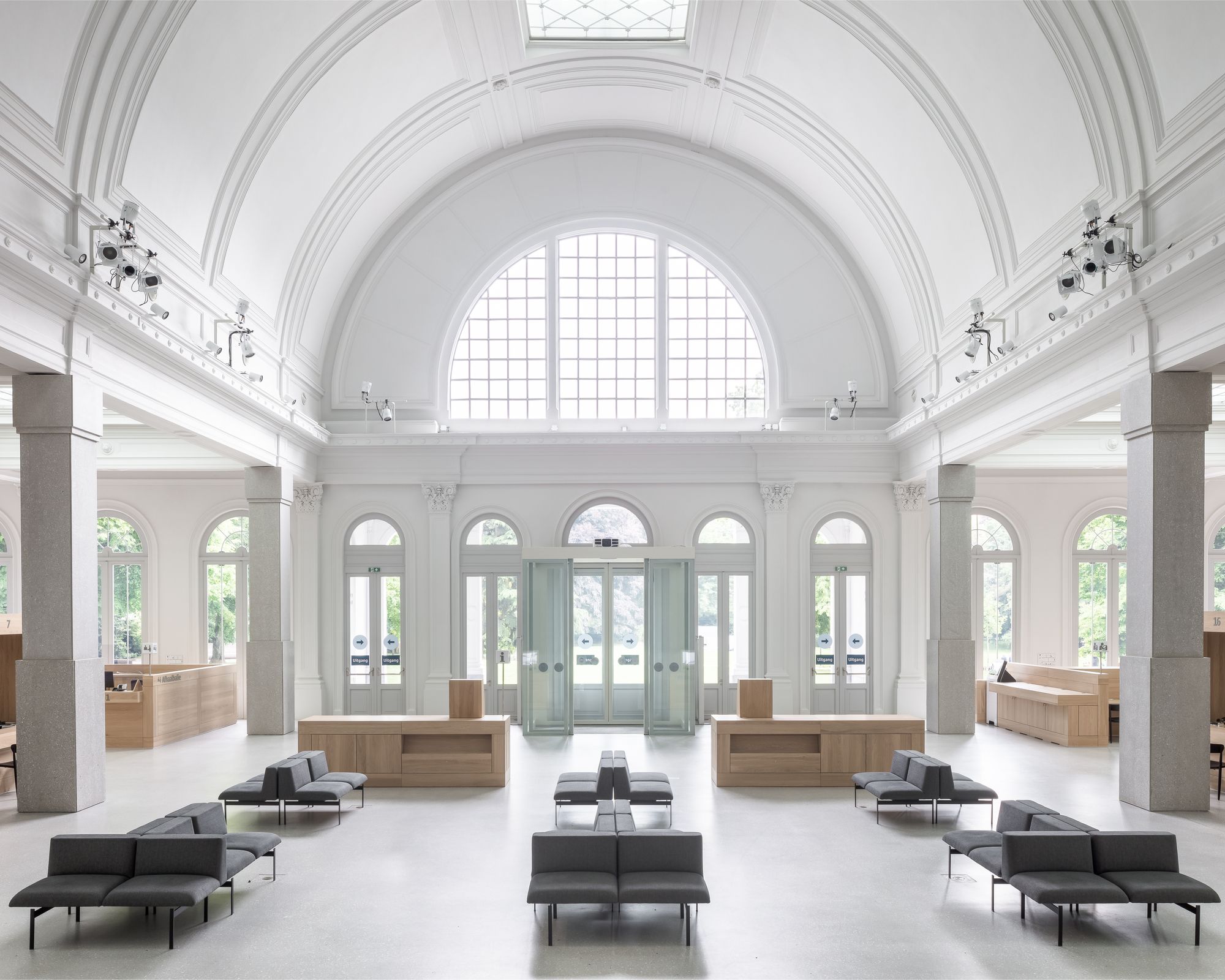 Ruime zaal met wit, gewelfd plafond en lage banken om te wachten.