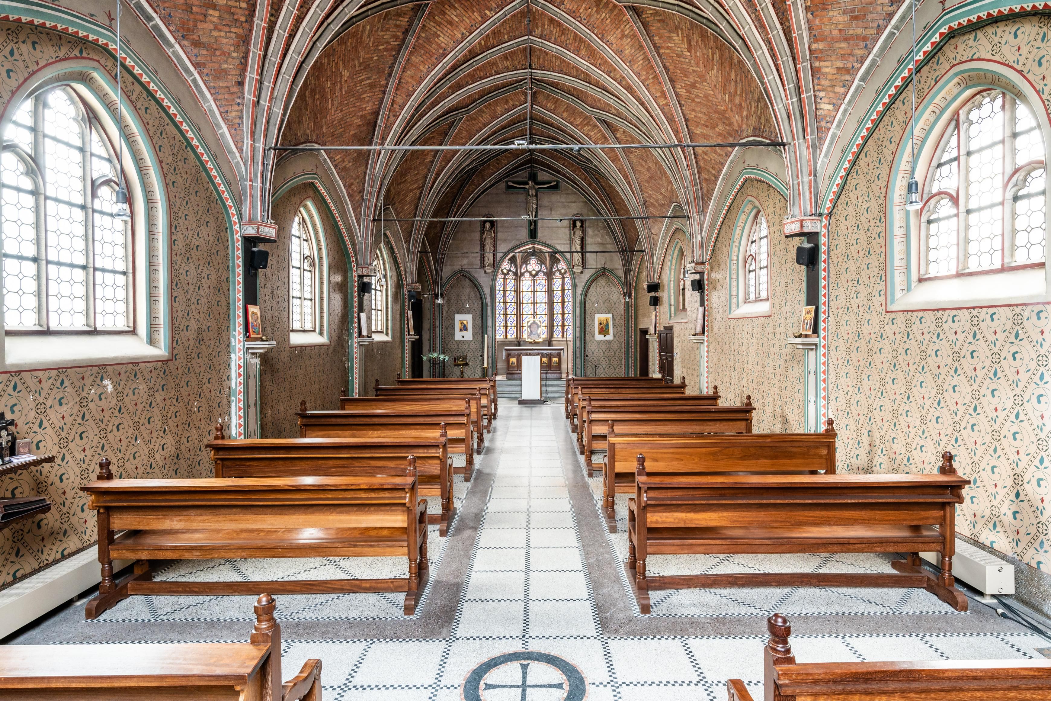 Beeld van gotische zaalkerk met houten banken.