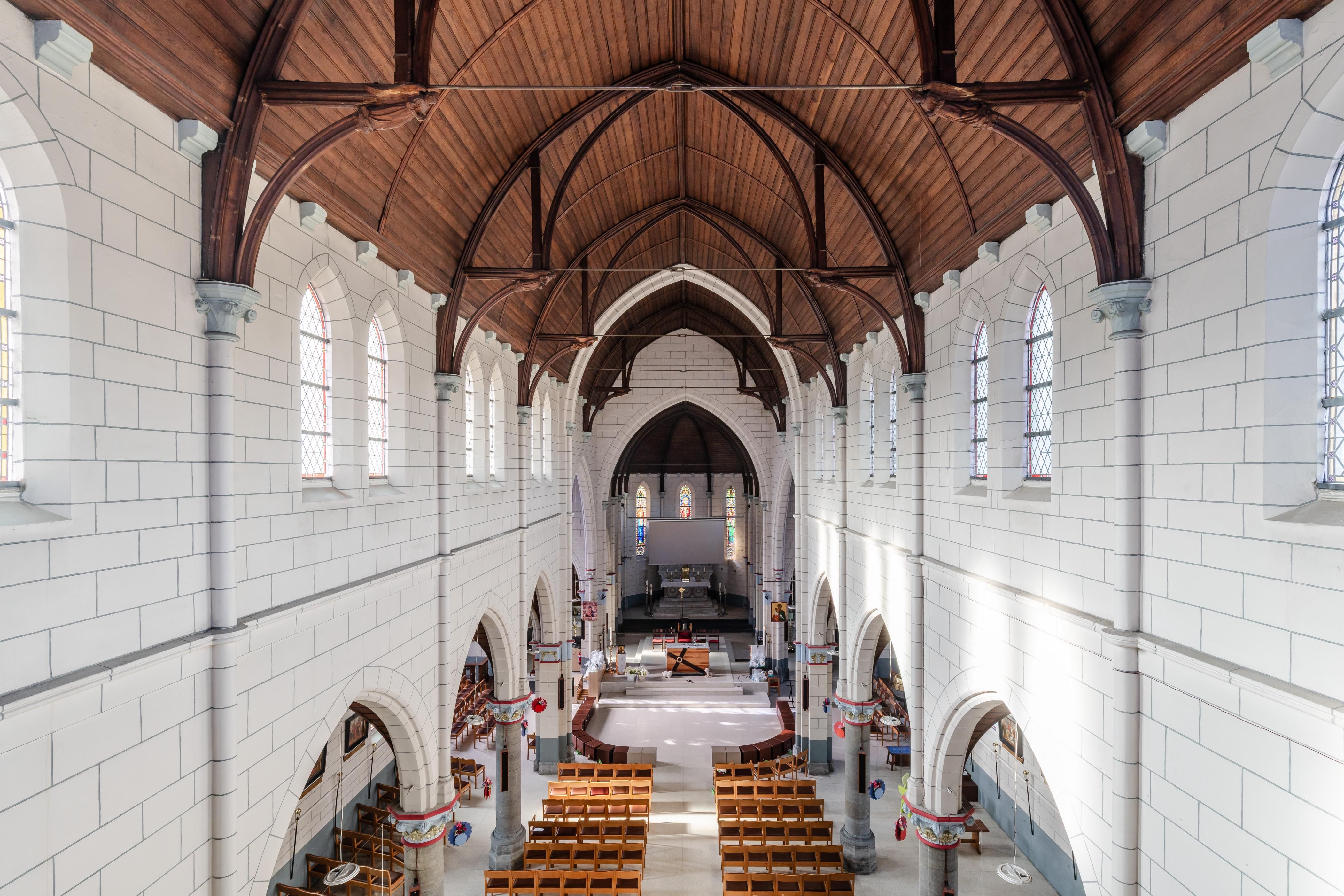 Het schip van de kerk met sober interieur en houten plafond.
