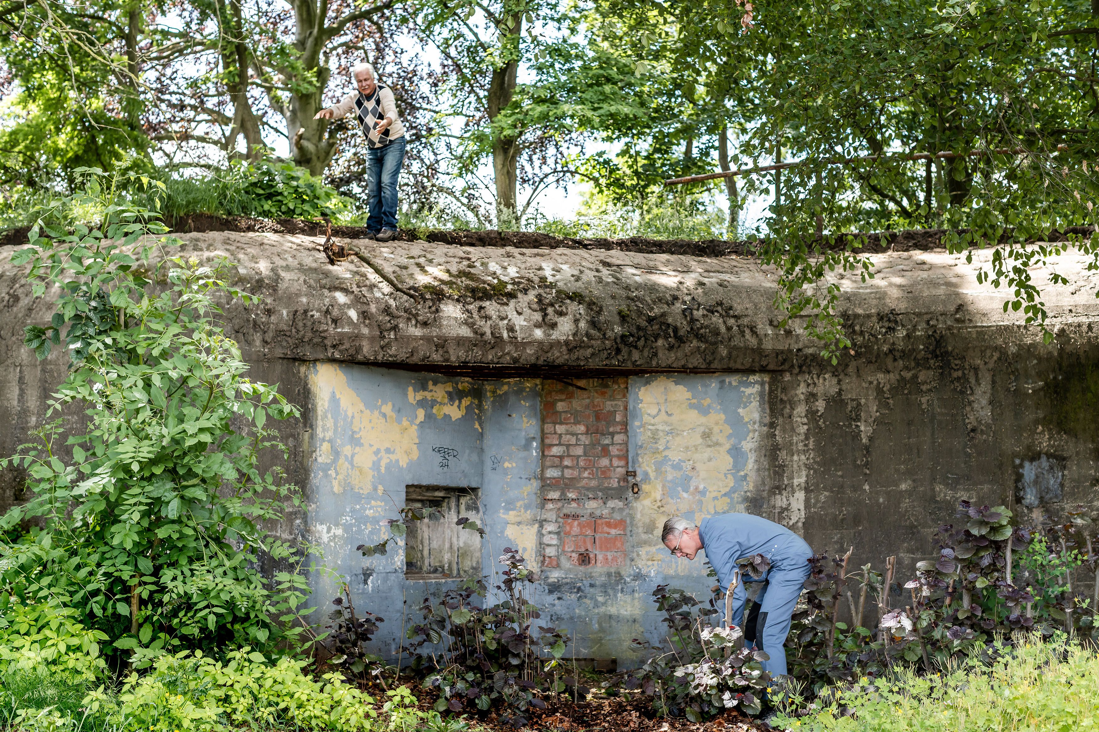 Man wiedt onkruid naast een bunker