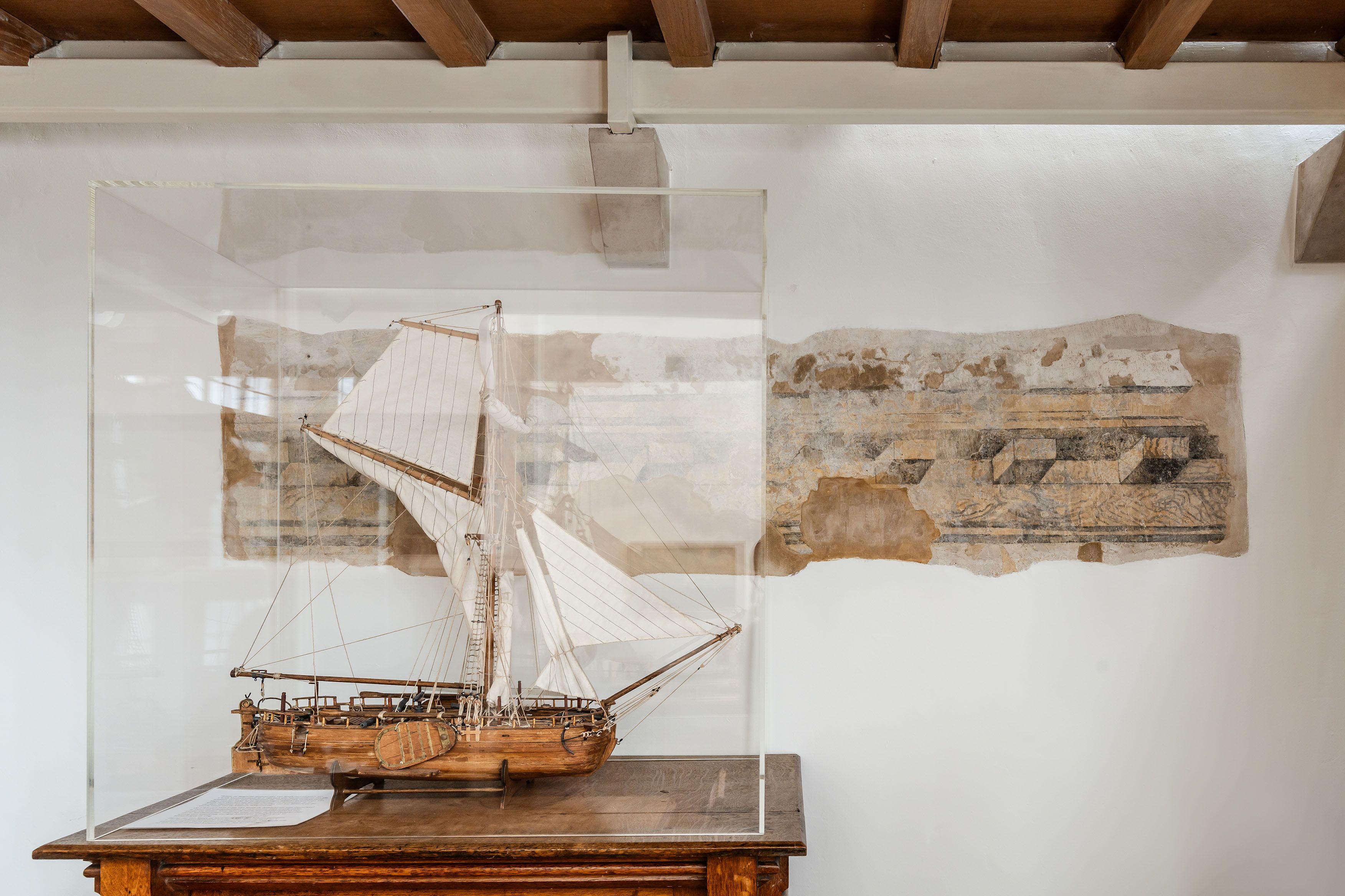 Schaalmodel van een schip onder een glazen stolp.