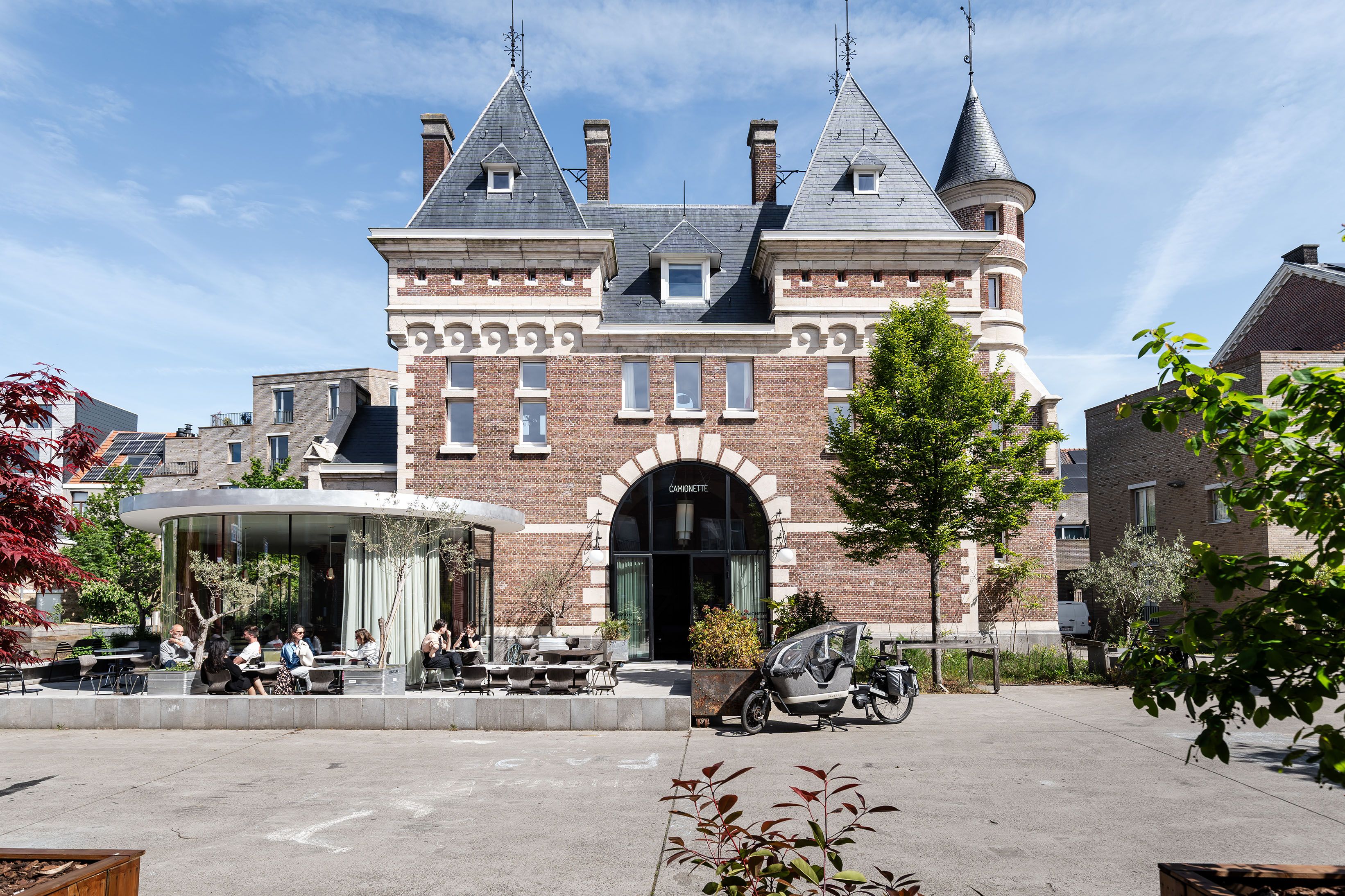 Poortgebouw van het voormalig militair hospitaal. Het bakstenen gebouw met leien dak is uitgewerkt als een klein kasteeltje met een rondboogvormige doorgang, vierkante torens met puntvormige bekroning en ronde torentjes met spits.