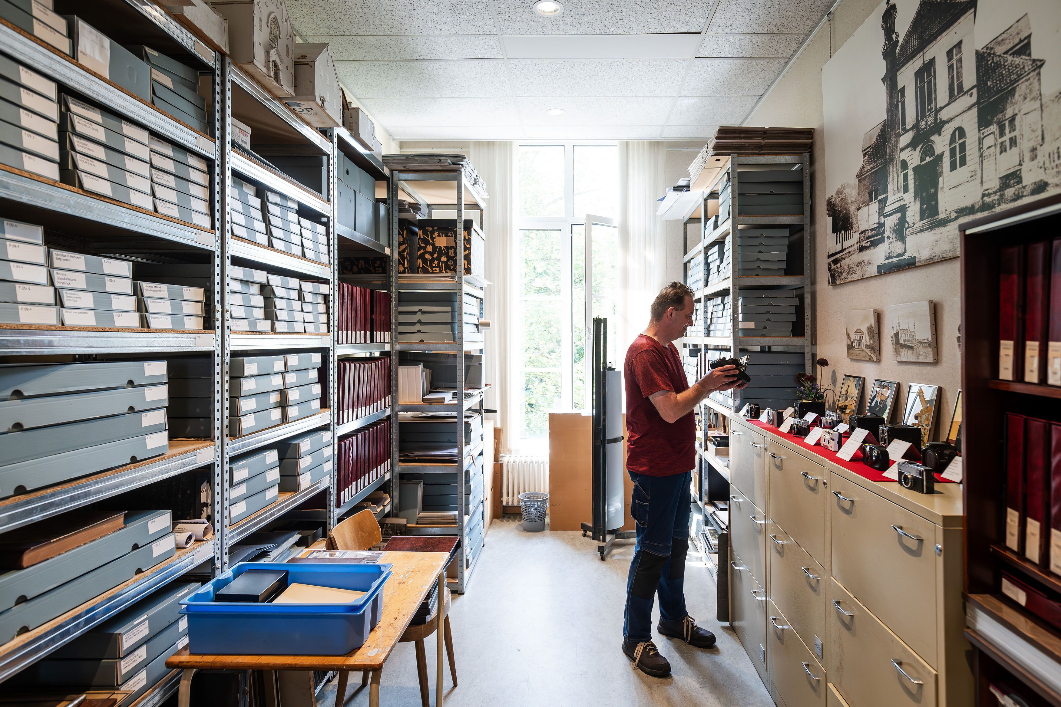 Archiefruimte met kasten en een vrijwilliger die aan het werk is in het archief