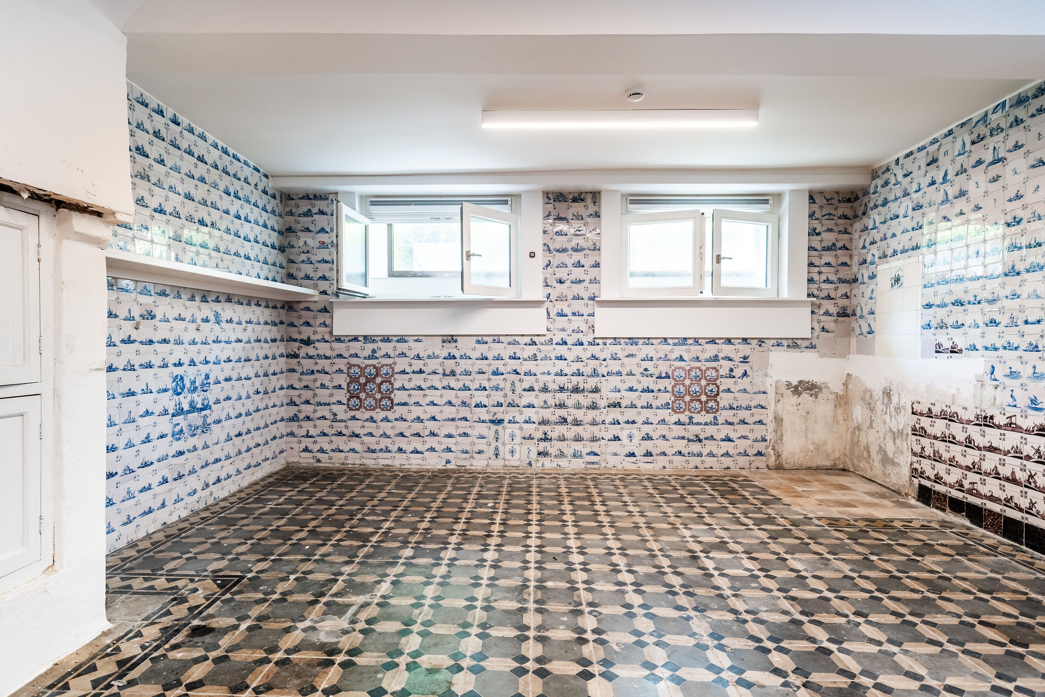 Overzichtsfoto van de tegelkamer met aan de drie afgebeelde wanden, van vloer tot plafond blauw-witte tegels.