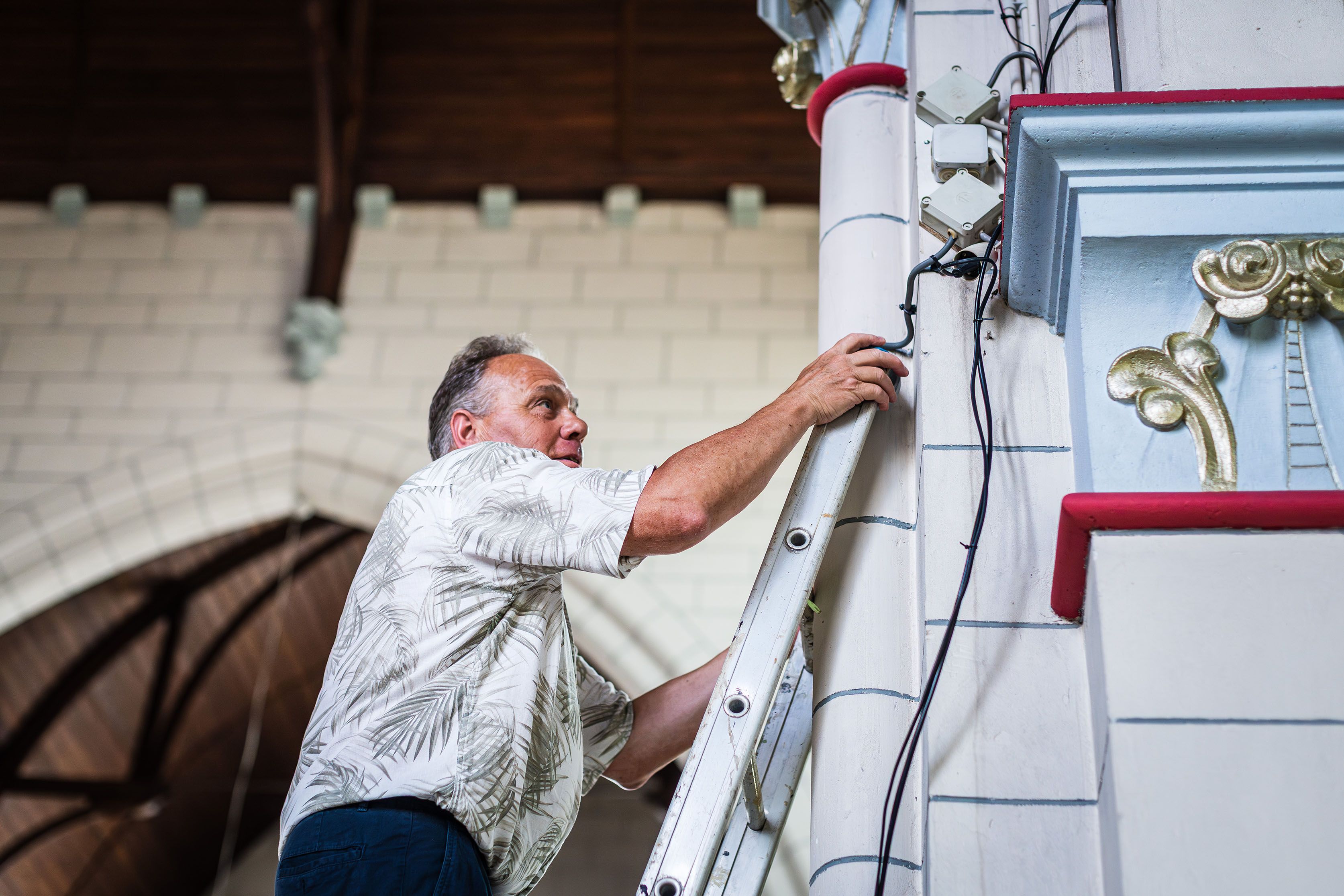 Een vrijwilliger werkt op een ladder aan het interieur van de kerk.