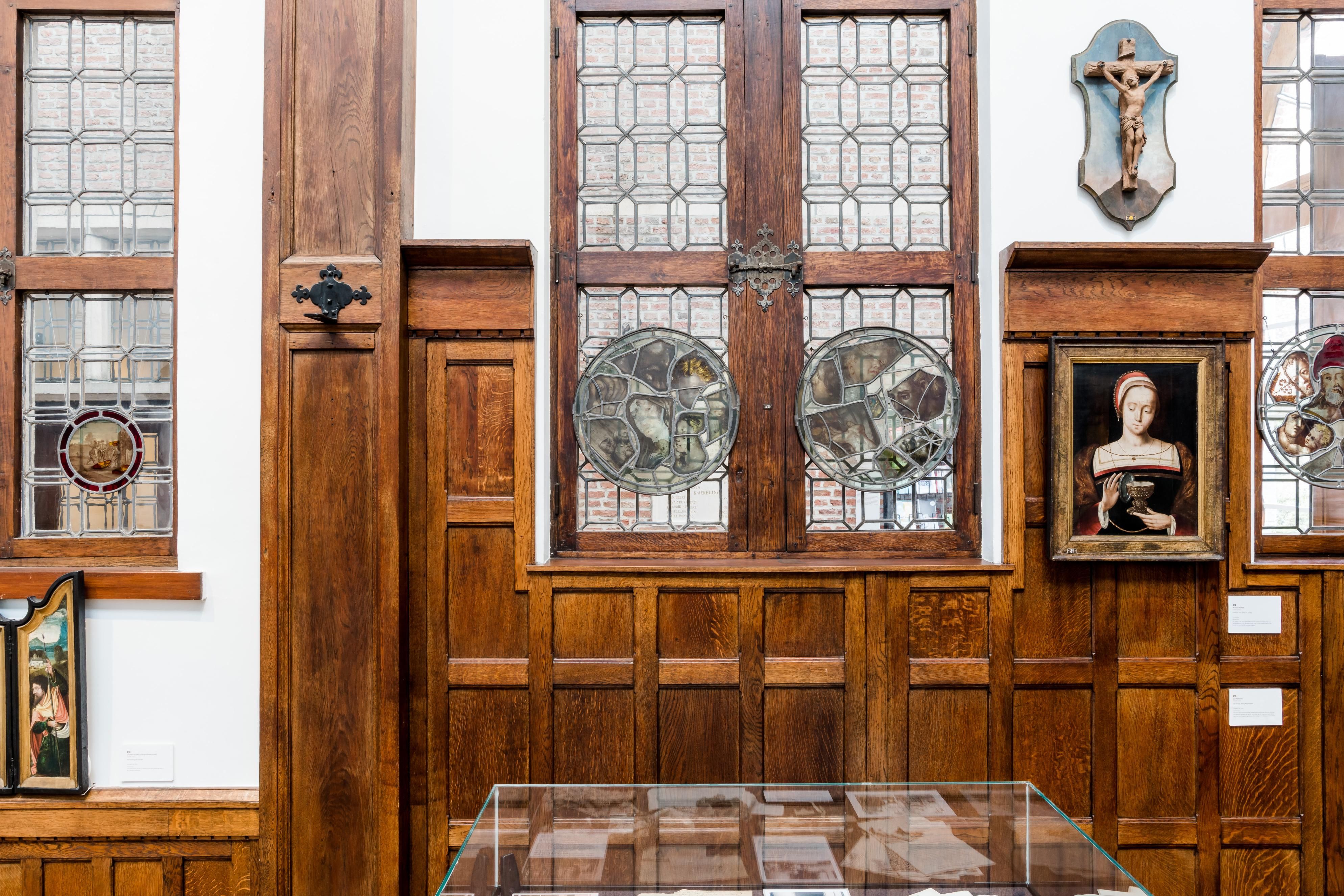Witte muur met glas-in-loodramen en een houten lambrisering