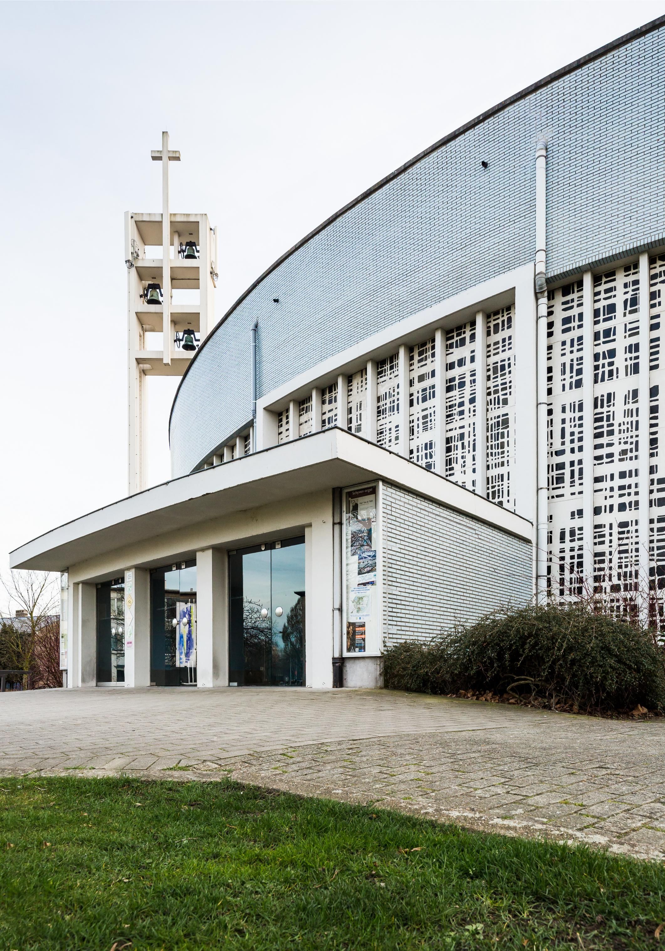 Inkomhal kerk met daarachter een halfronde gevel met glas-in-beton.