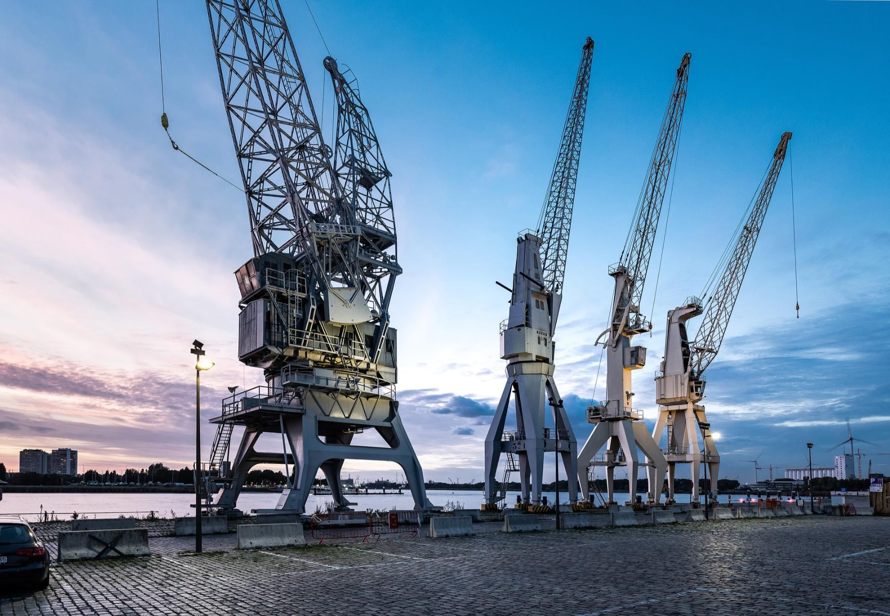 Vier kranen opgesteld langs de Scheldekaaien bij valavond.
