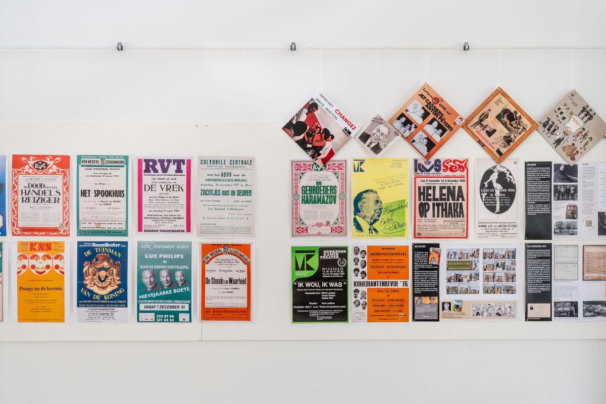 Een witte muur met kleurrijke posters van oude voorstellingen.