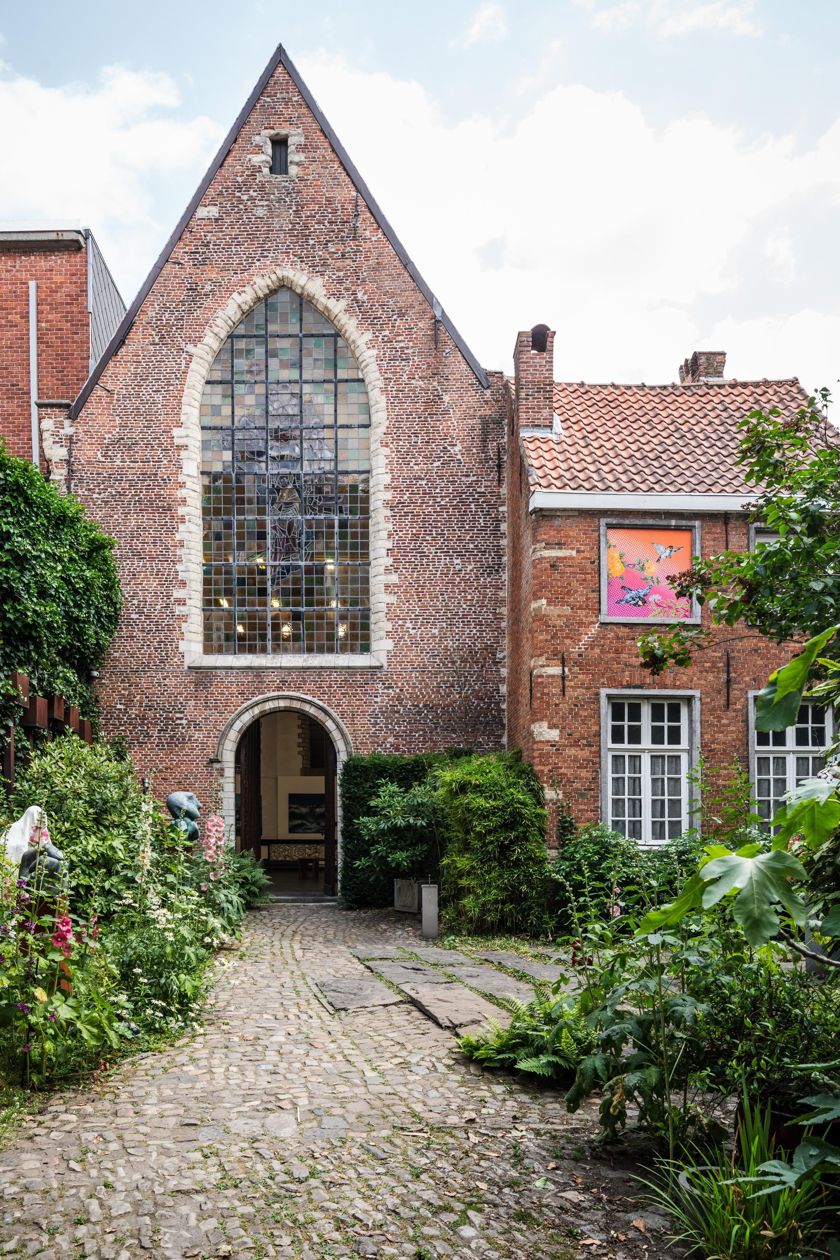Zicht op de kapel vanop het binnenplein, puntgevel met glasraam.
