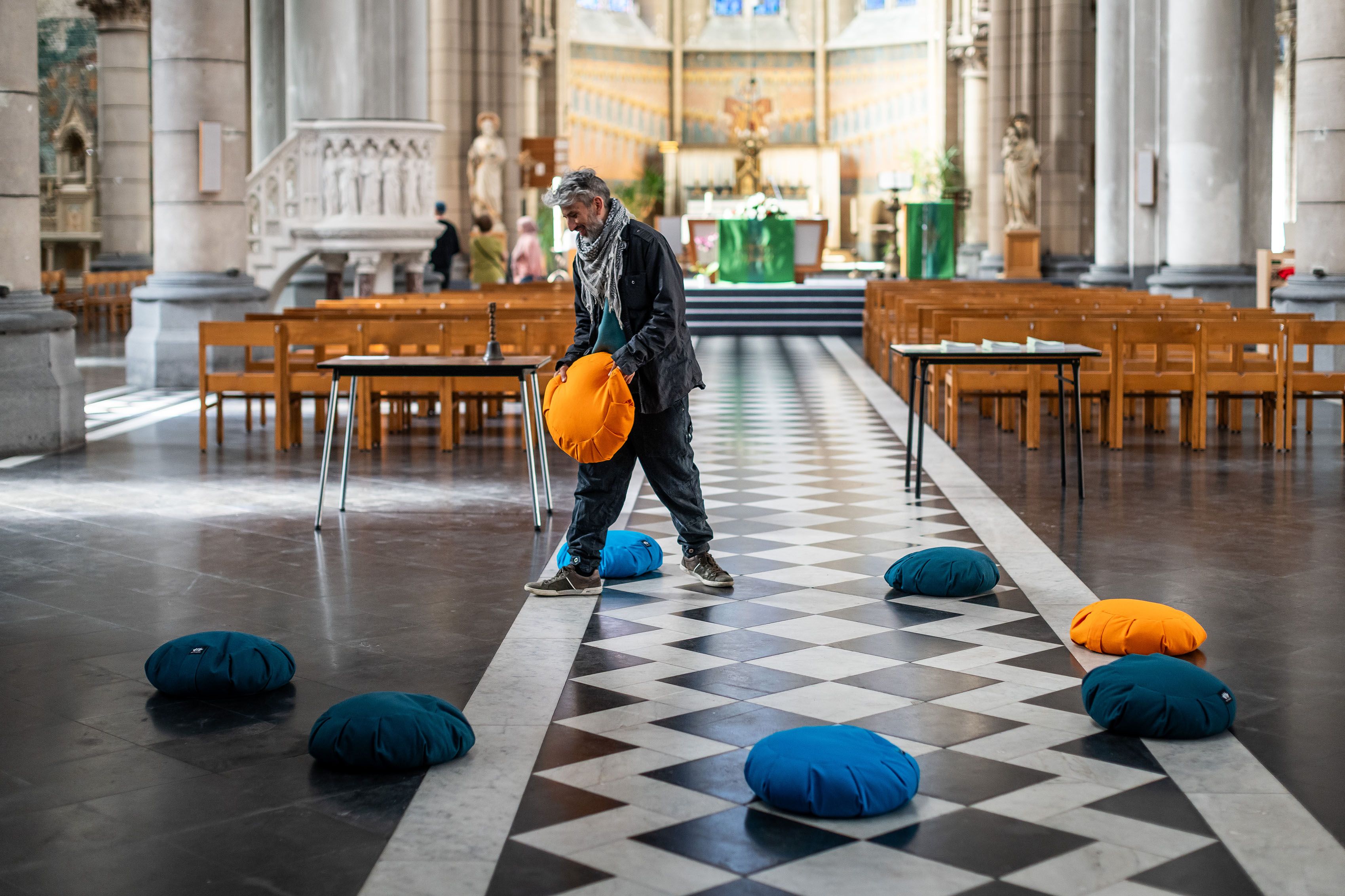 Man ligt ronde kussens in blauw en oranje in een cirkel op de vloer van de Heilige Familiekerk.