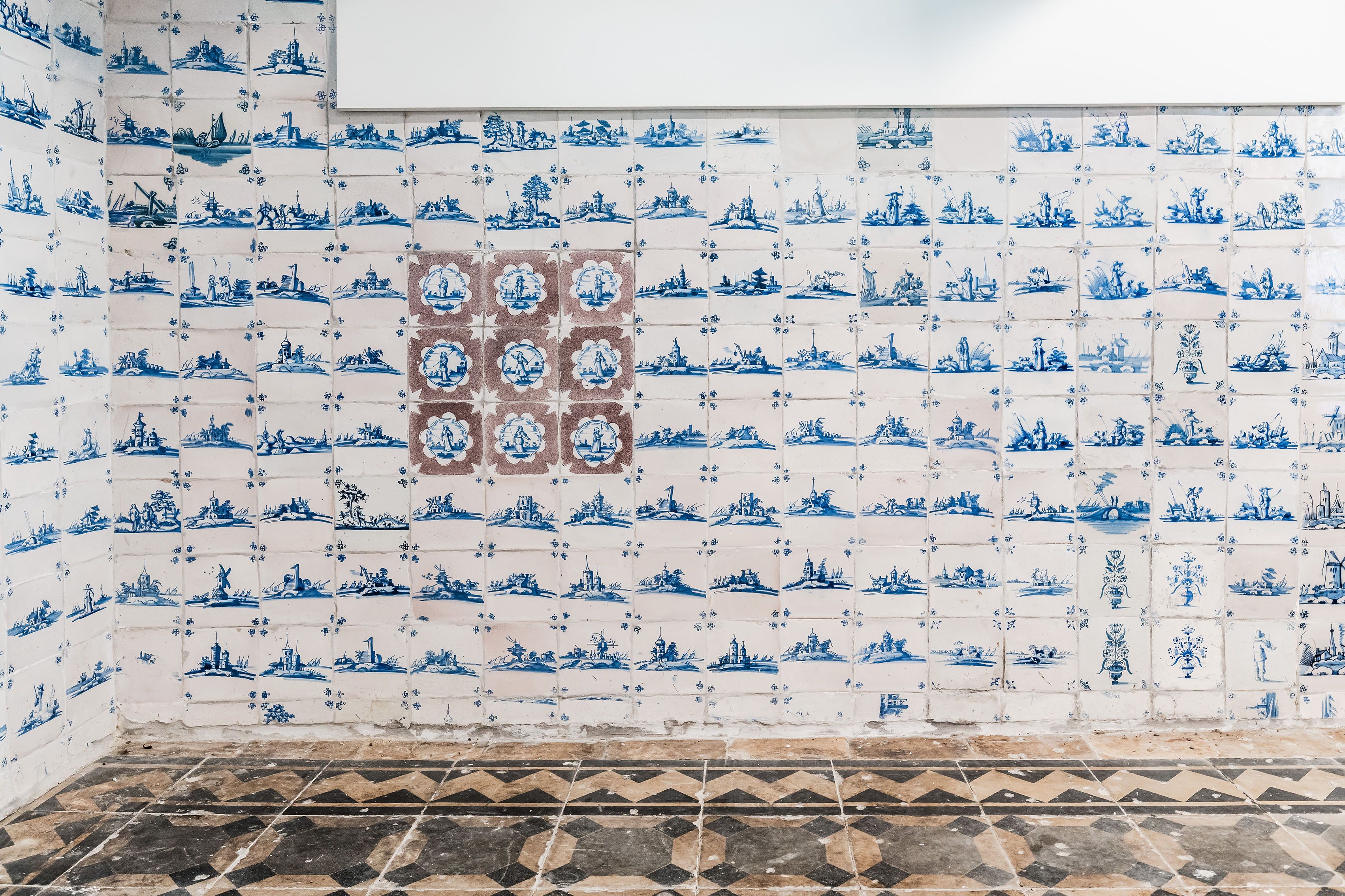 Detail van één van de muren in de voormalige kelderkeuken. De muur is van vloer tot plafond voorzien van blauwwitte tegels.