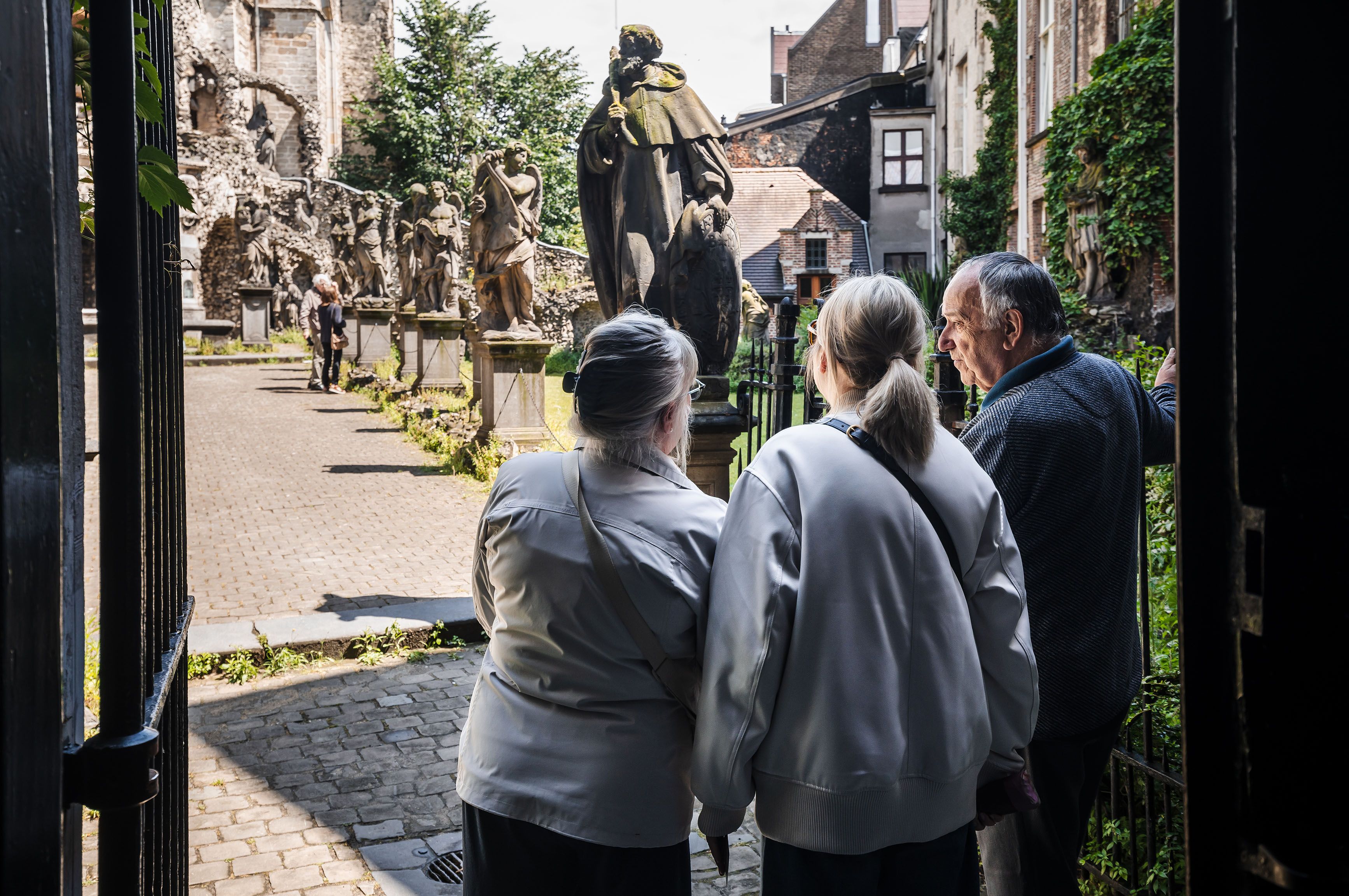 2 vrouwen en 1 man kijken vanuit een deur naar de calvarieberg