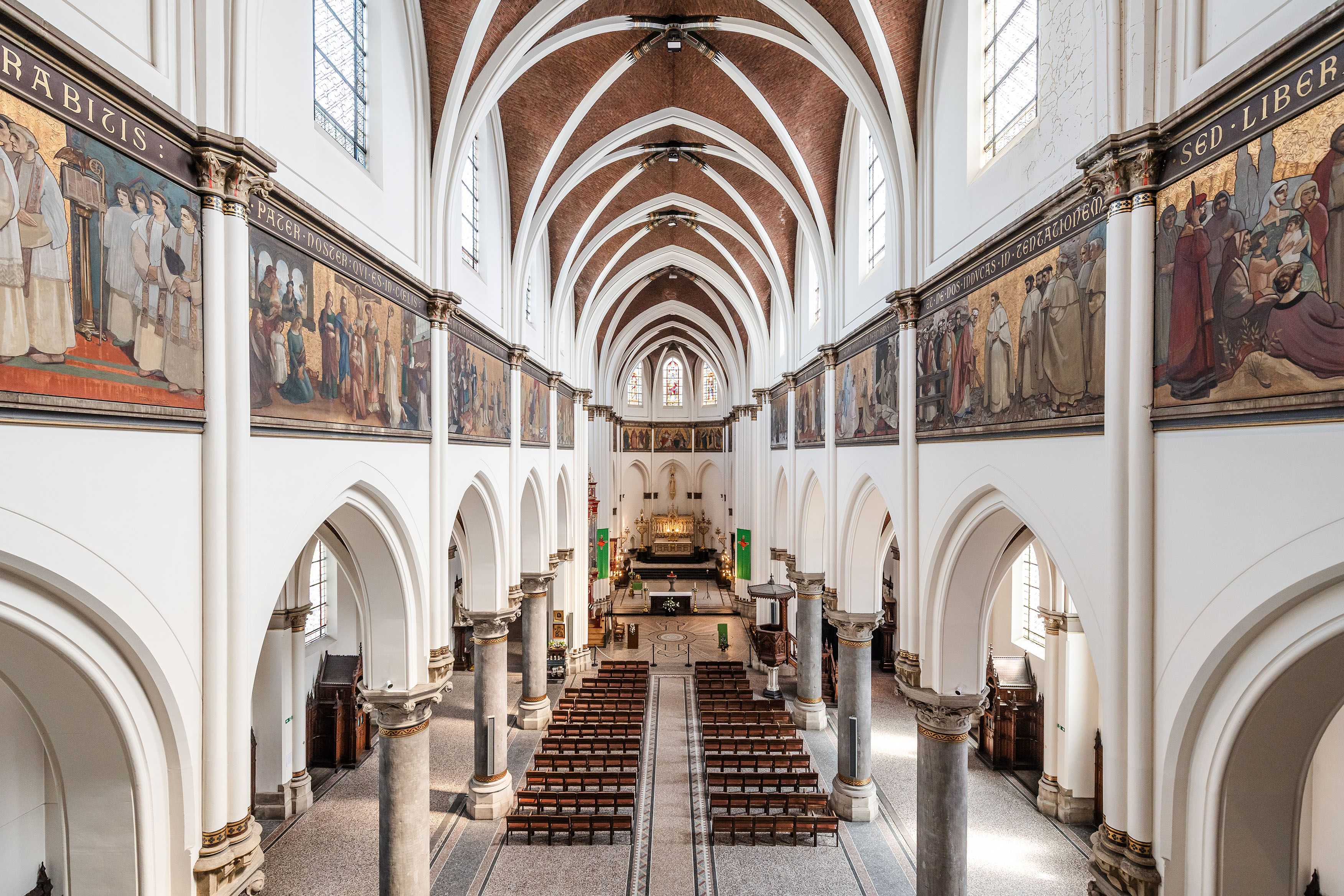 Zicht vanop het balkon naar het altaar van de Sint-Norbertuskerk, kruisribgewelven en muurschilderingen.