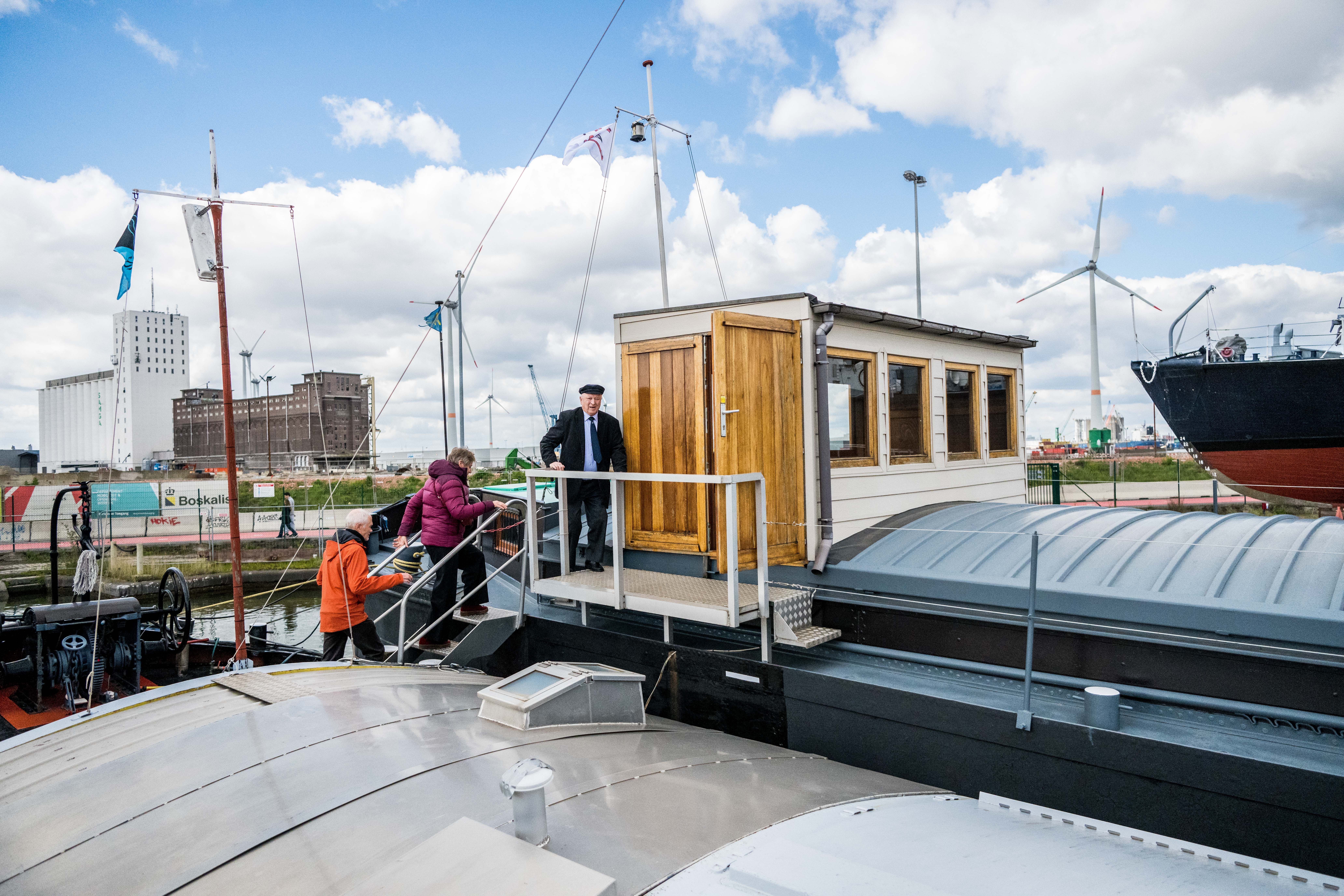 3 schepen liggen naast elkaar 4 mensen wandelen op een trap om een schip binnen te gaan