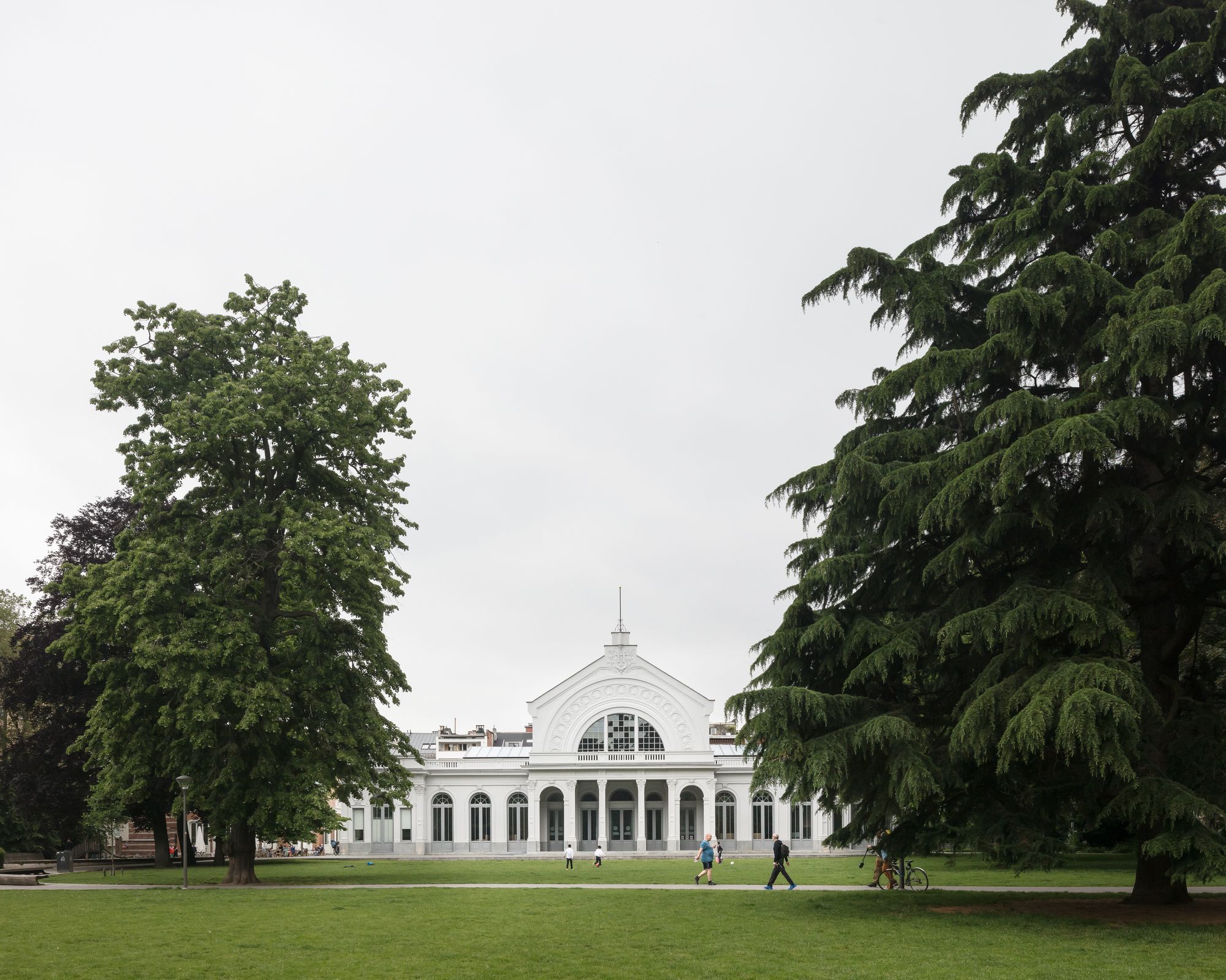 Harmonie vanuit het Harmoniepark, vanop afstand met grote bomen aan beide zijden van het beeld.