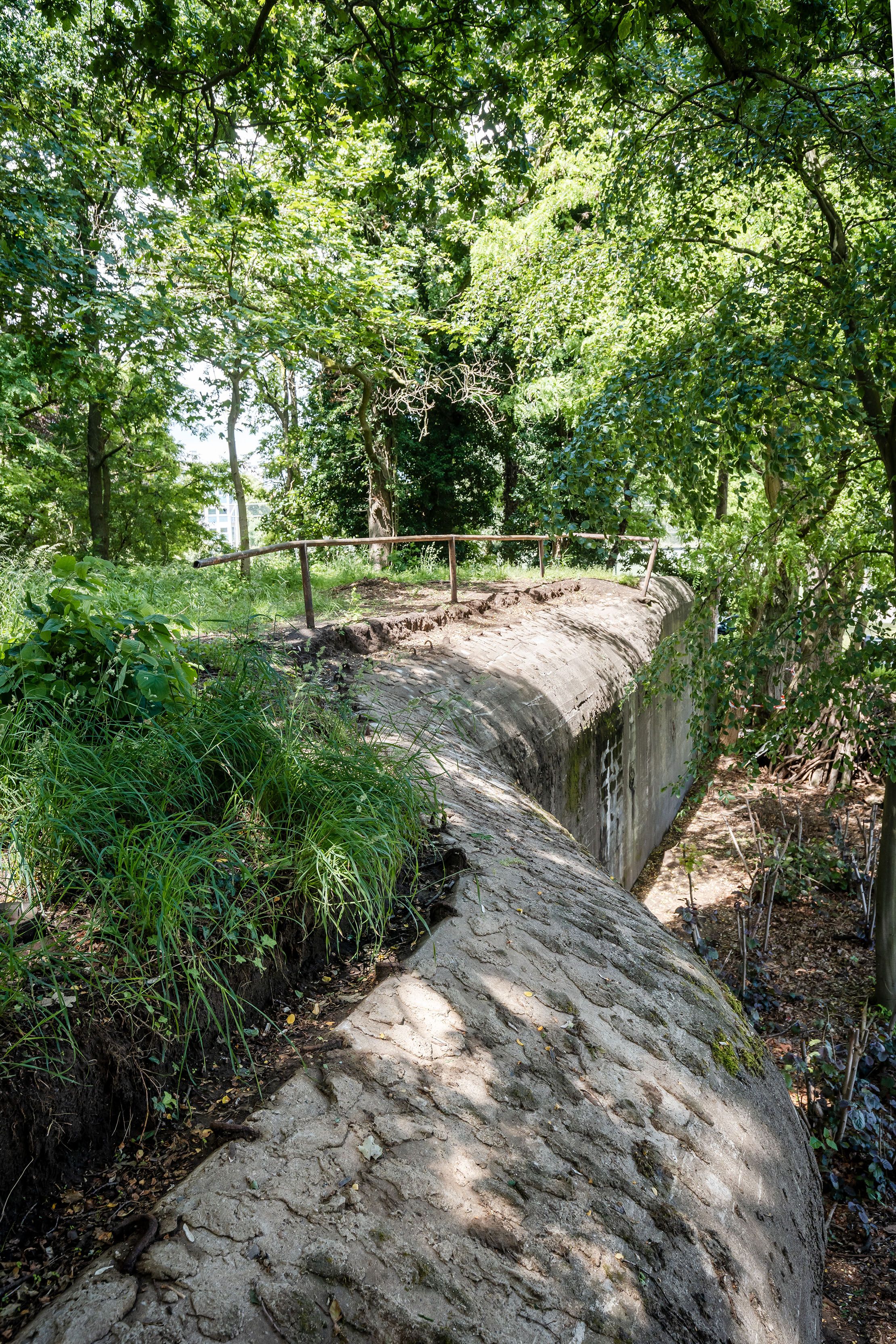 Bunker in het park Den Brandt. De lange, betonnen bunker is verstopt tussen de beplanting van het park.