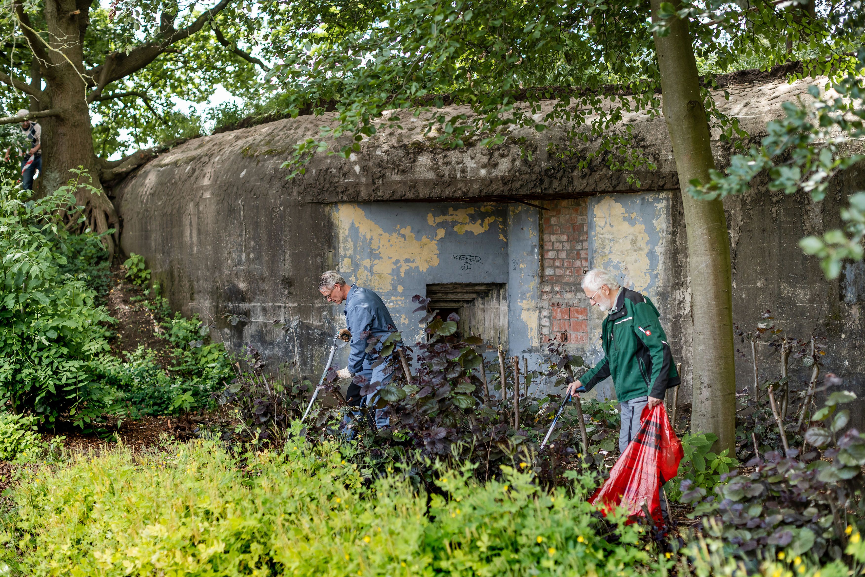 2 mannen rapen afval op naast een bunker