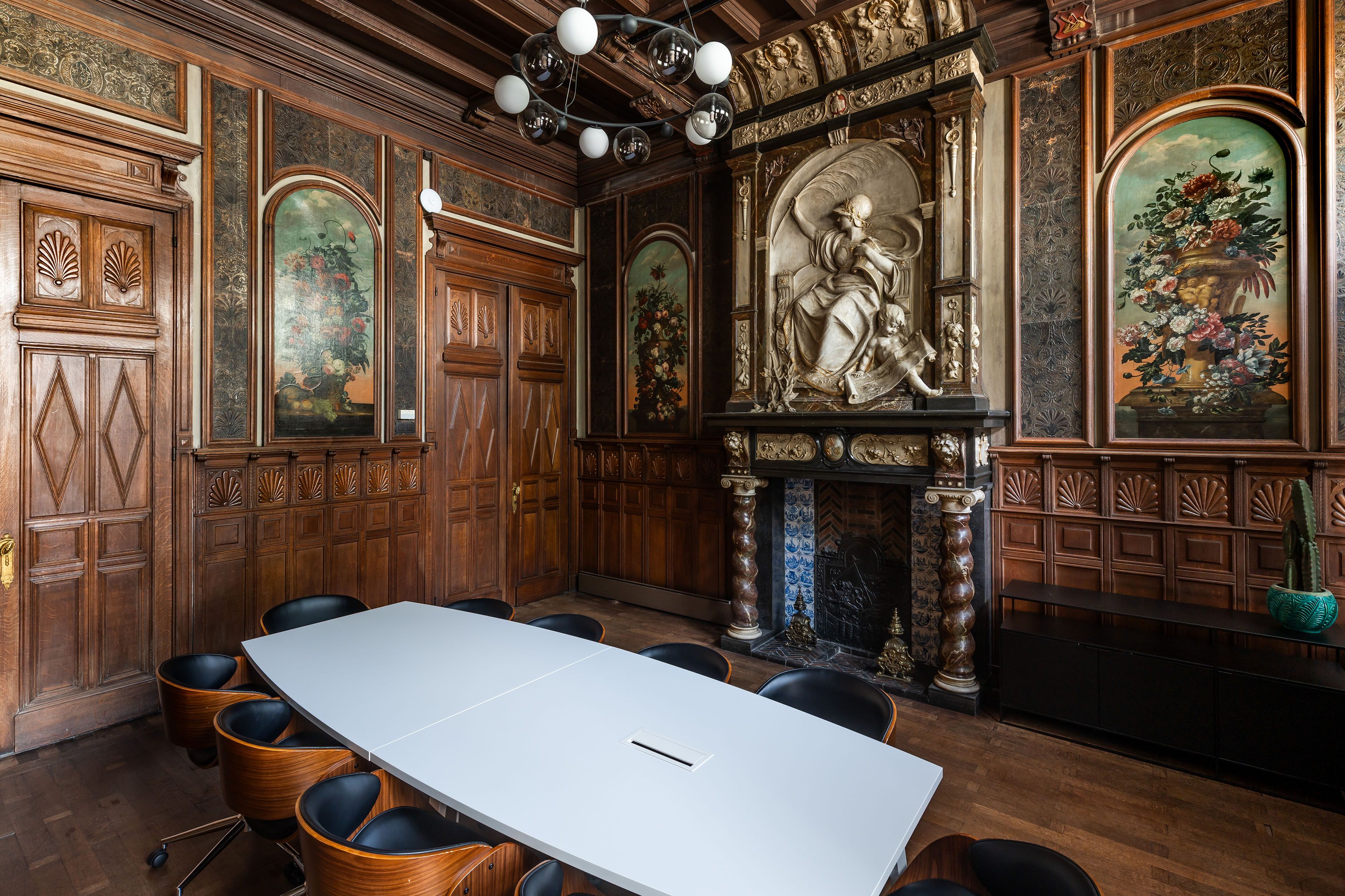 Kamer met houten wandpanelen en een open haard met een beeld in reliëf erboven.