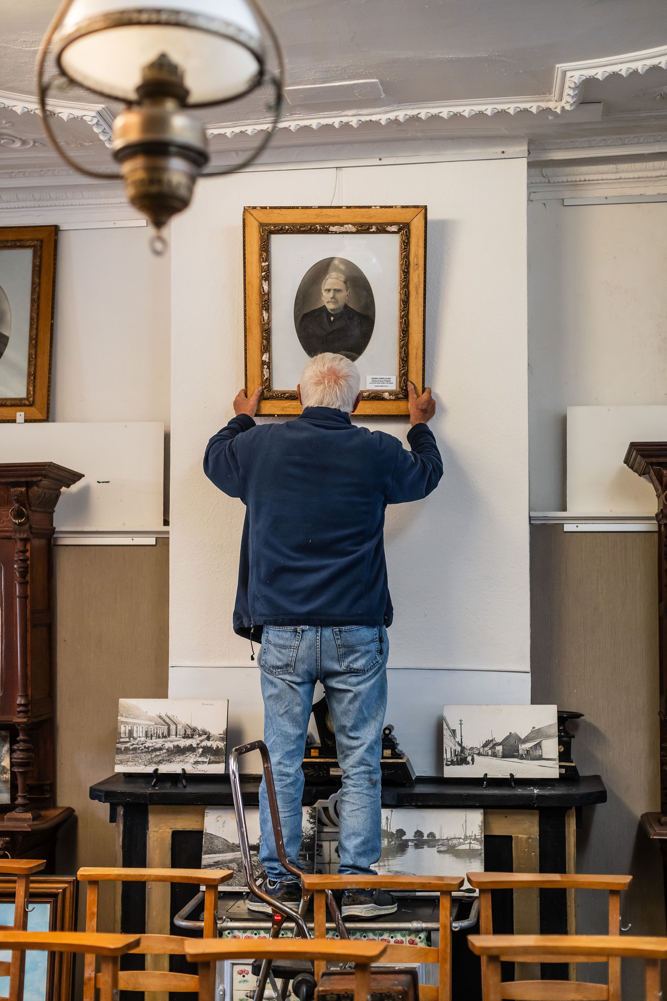 Een vrijwilligers hangt een kader op.
