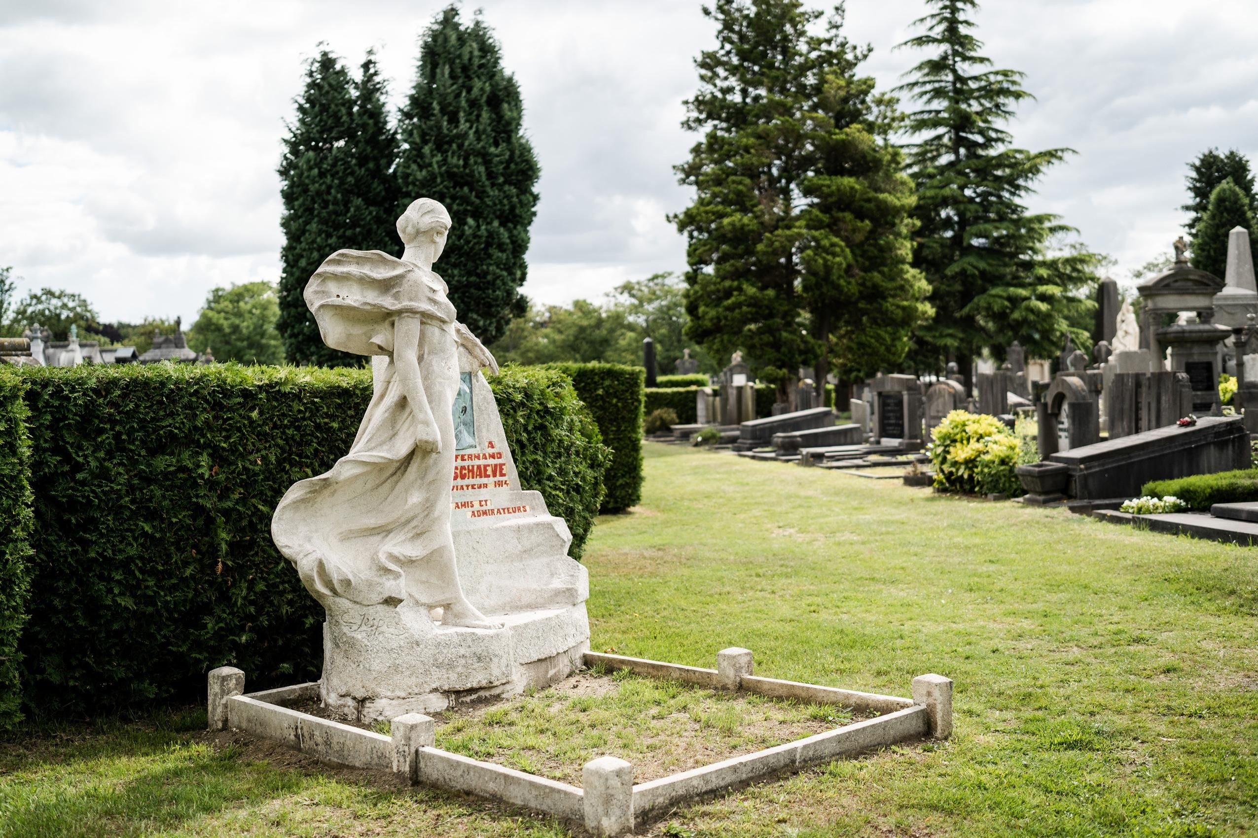 Grafmonument in witte natuursteen met een gebeeldhouwde vrouwenfiguur.