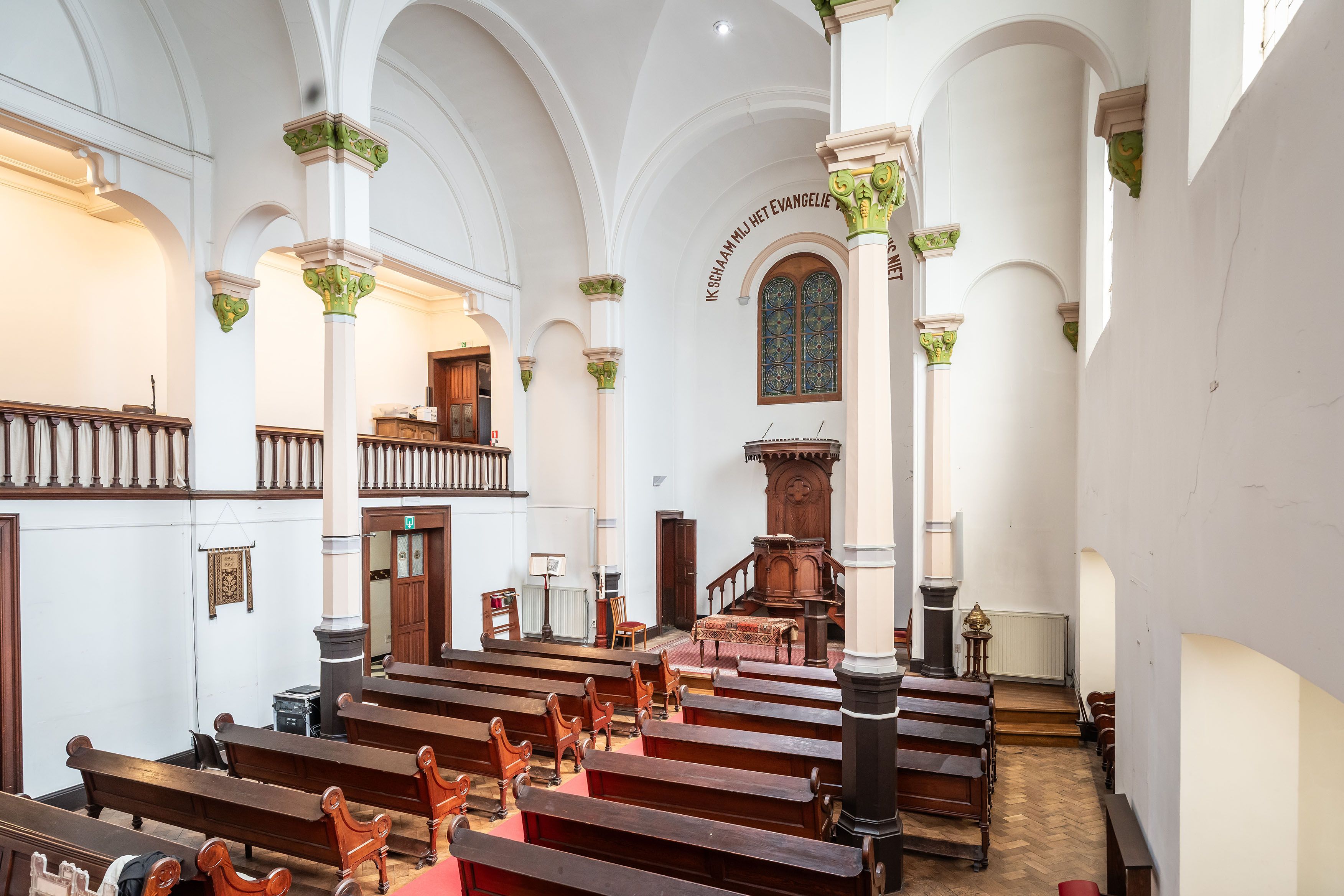 Het sobere interieur van de kerk met witte muren, gewelfde plafonds en met goud versierde kapitelen aan de zuilen.