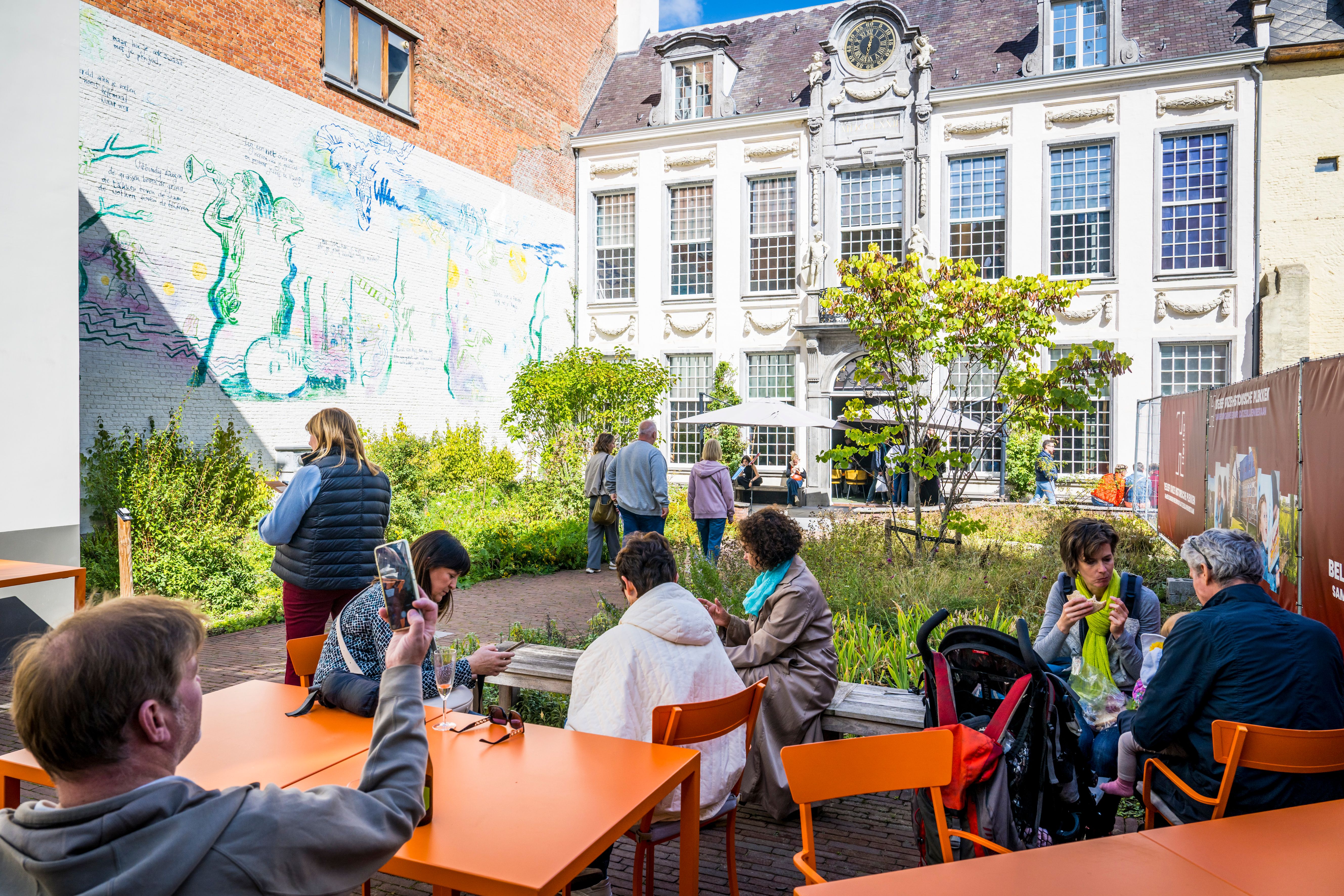 Bezoekers zoeken schaduw op in de gezellige binnentuin