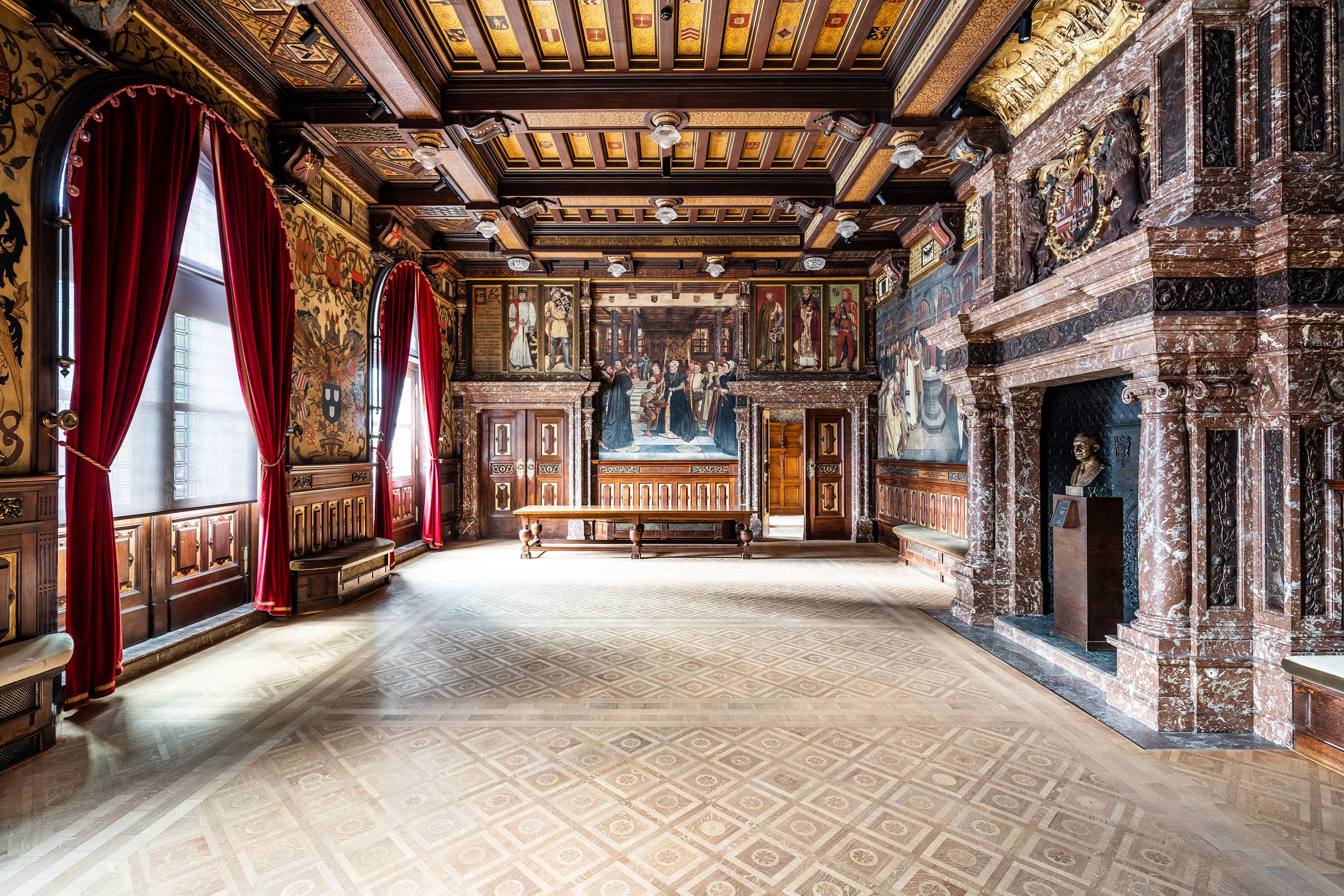 Rijkelijk interieur stadhuis met rode fluwelen gordijnen, schouwen in orde marmer, plafond in hout en goud, parketvloer in ruitvorm