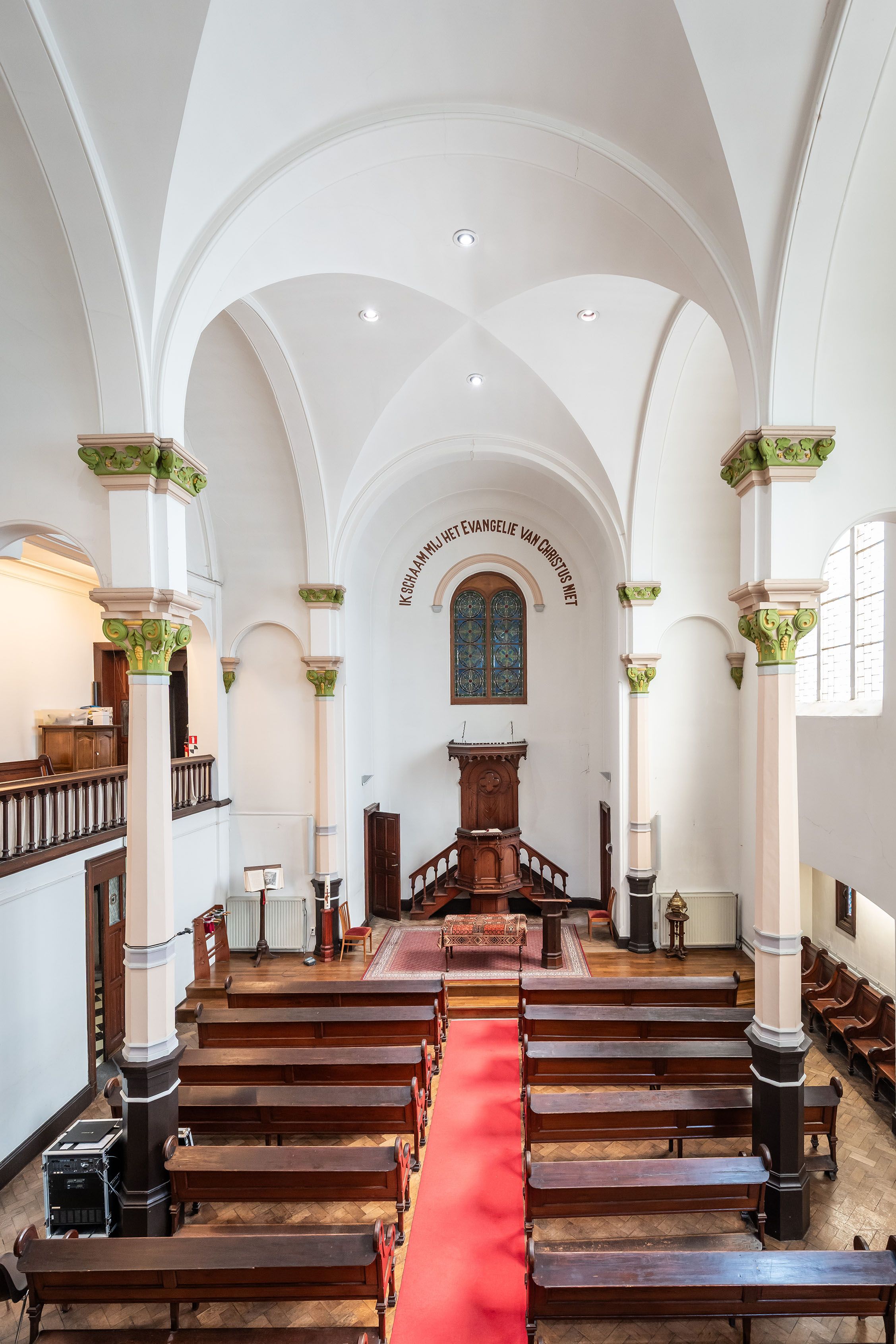 Het schip van de sober ingerichte kerk met banken en vooraan het altaar.