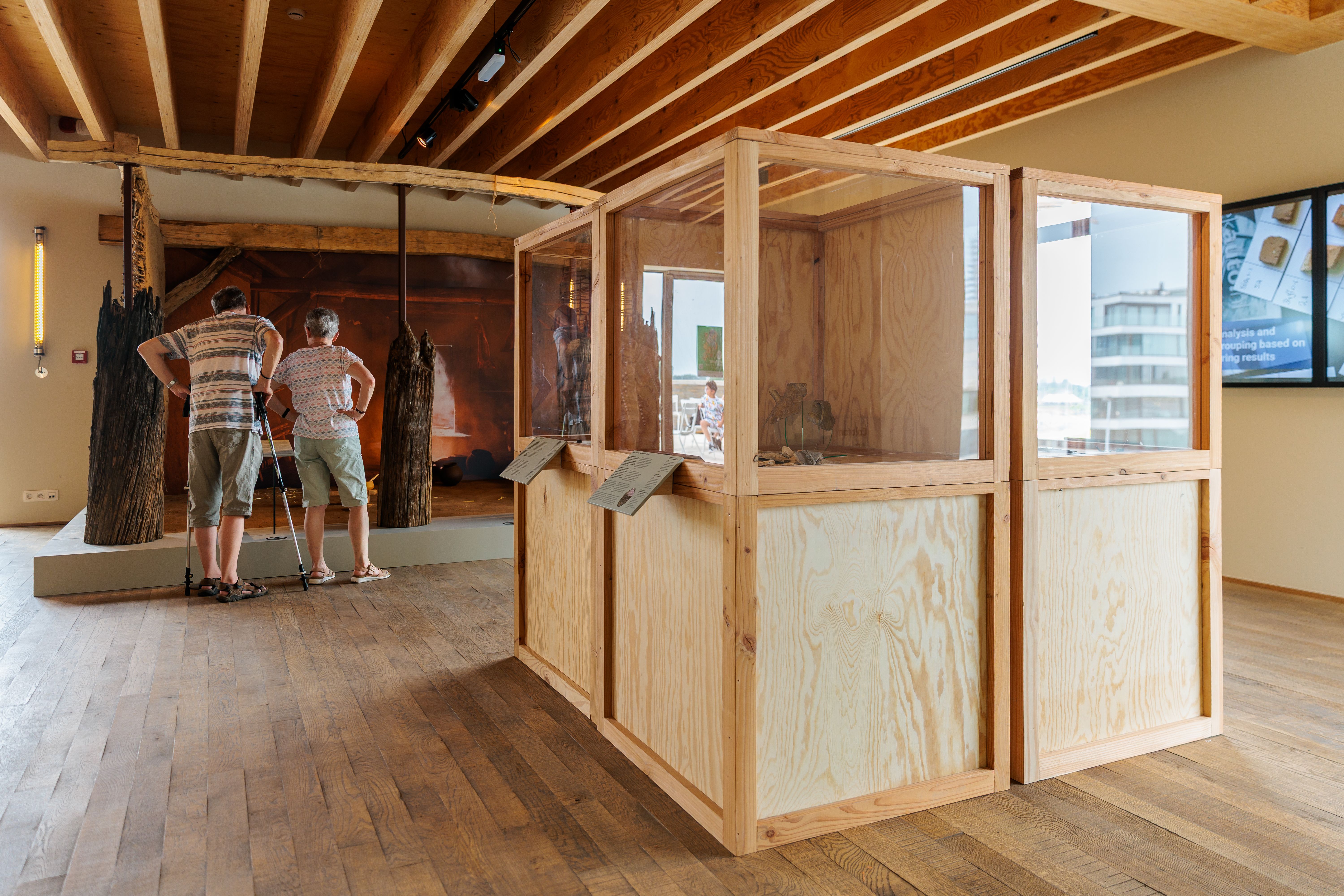 Bezoekers bekijken een replica van een 10de-eeuws woonwerkhuis nagebouwd met oude materialen zoals hout en leem