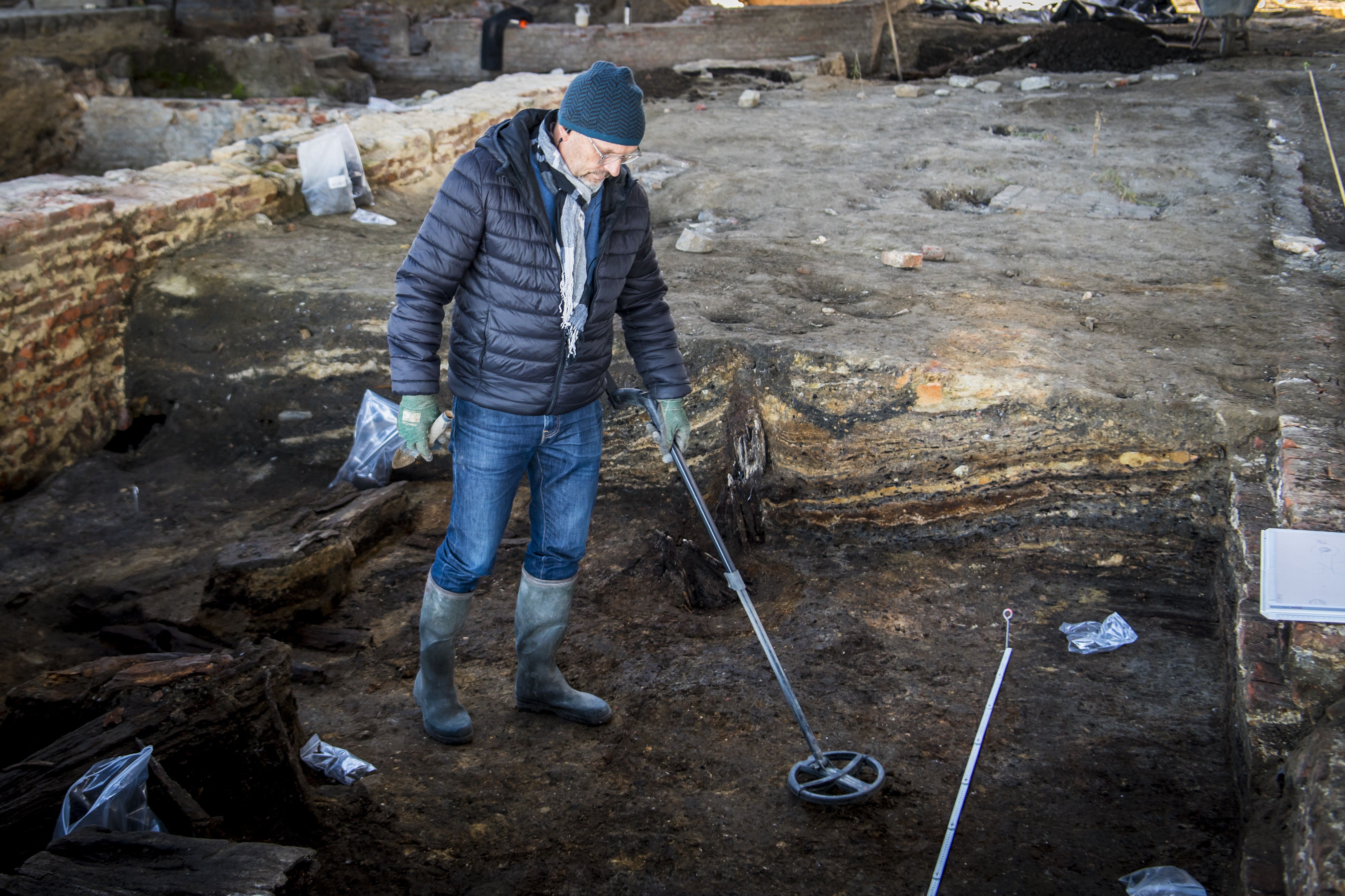 Een vrijwilliger-metaaldetectorist zoekt met zijn metaaldetector metaal op de archeologische site van de Burchtzone, vlakbij Het Steen.