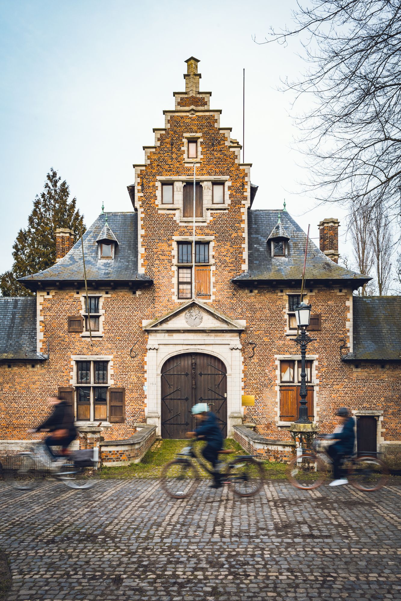Poortgebouw hofke van Roosendael met ervoor 3 fietsers.