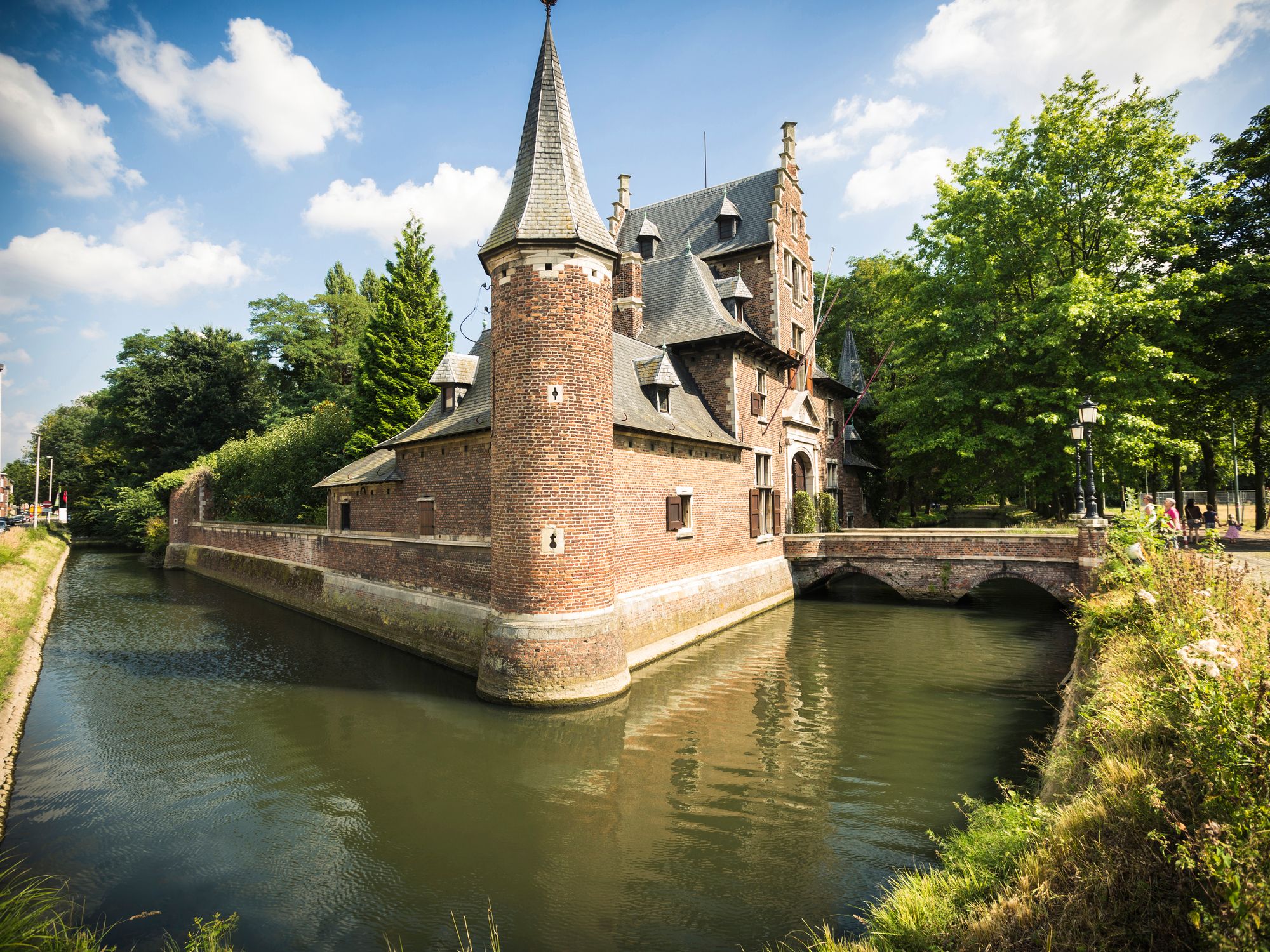 Zijaanzicht van het hofke van Roosendael. Zicht op de hoek van het gebouw met een toren en errond een gracht