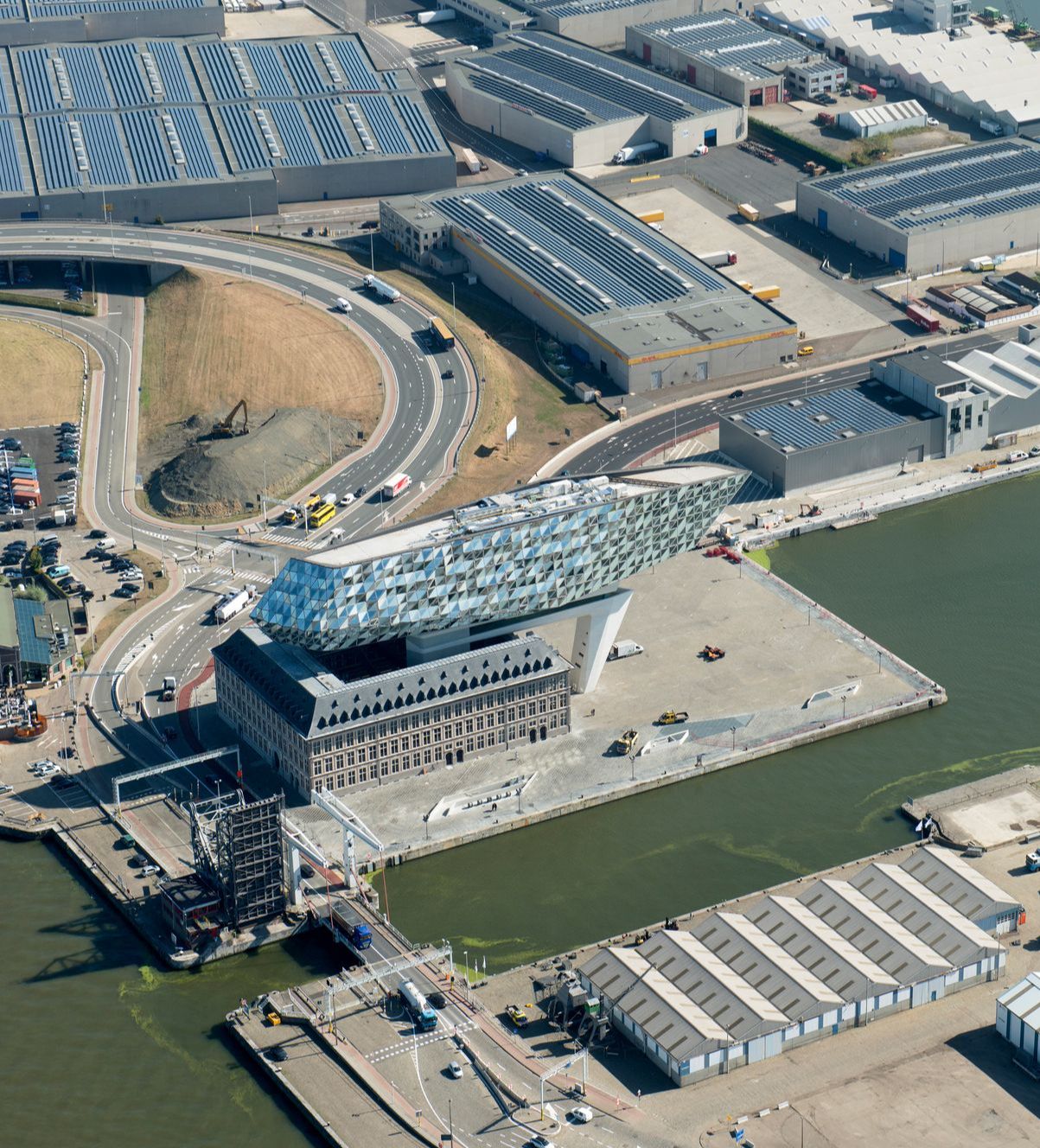 Luchtbeeld van het Havenhuis en zijn omgeving: grote magazijnen, dokken en de Schelde.