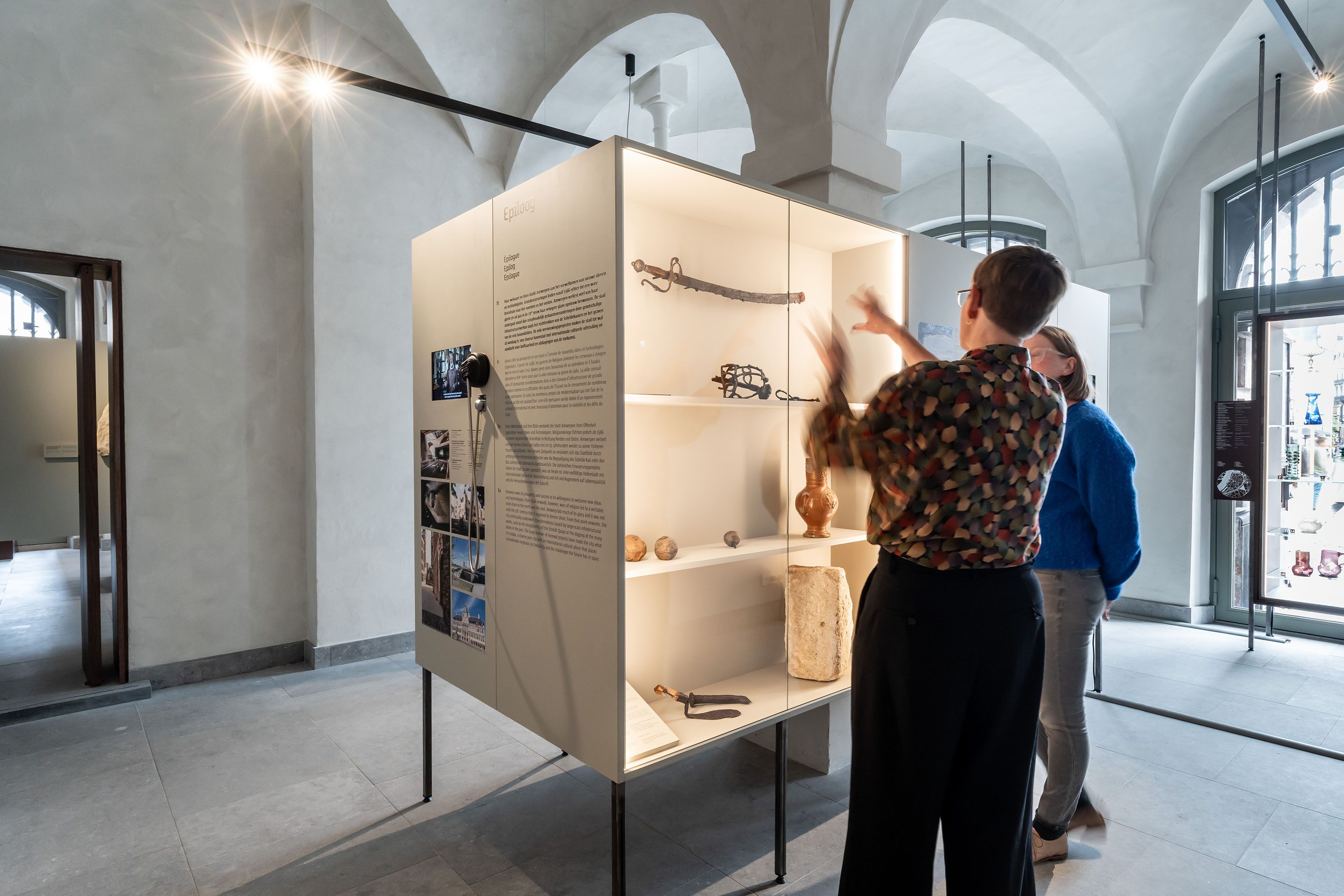 2 vrouwen kijken naar een tentoonstellingskast met archeologische voorwerpen