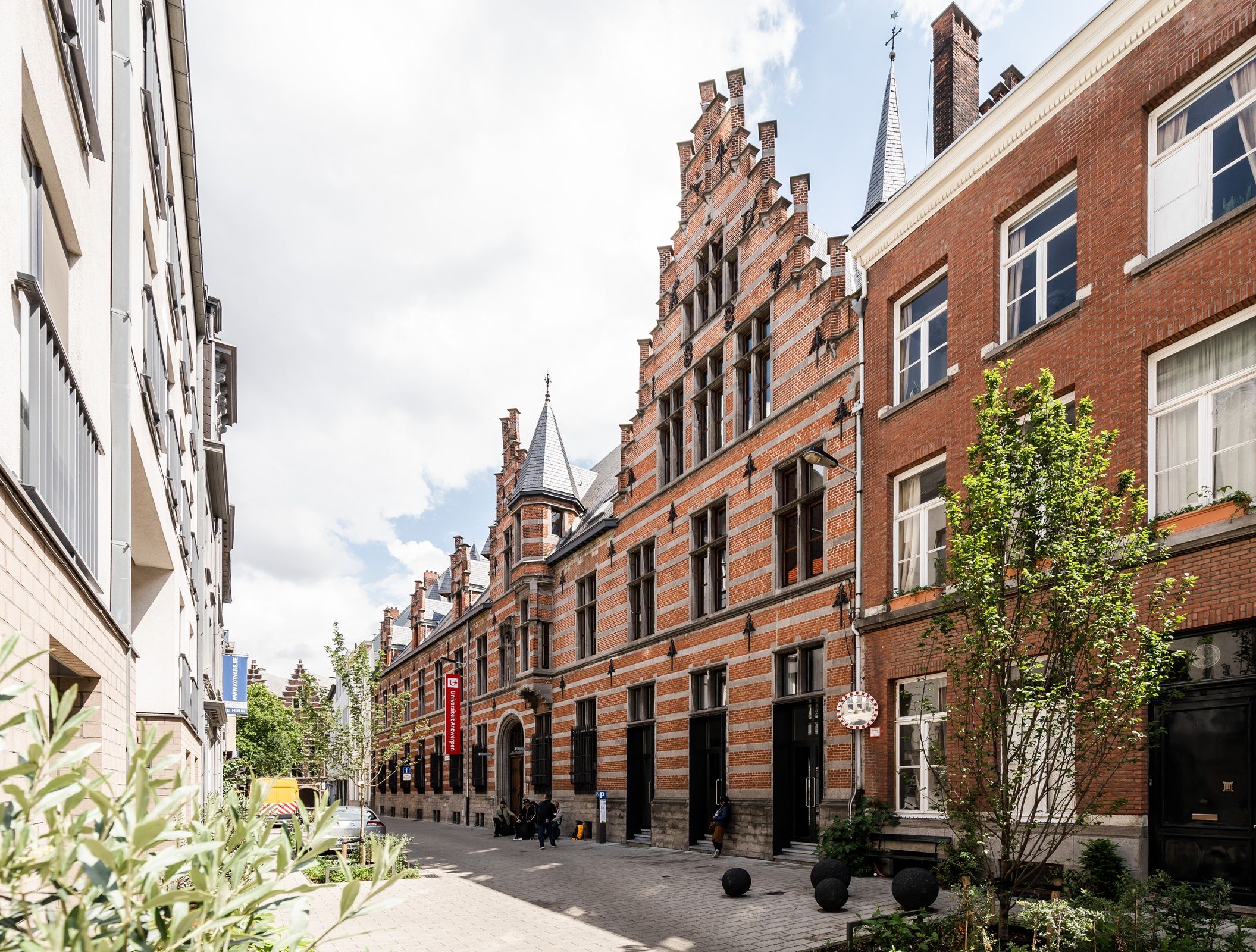 Straatbeeld met links witgeschilderde gebouwen en rechts gebouwen in rode baksteen