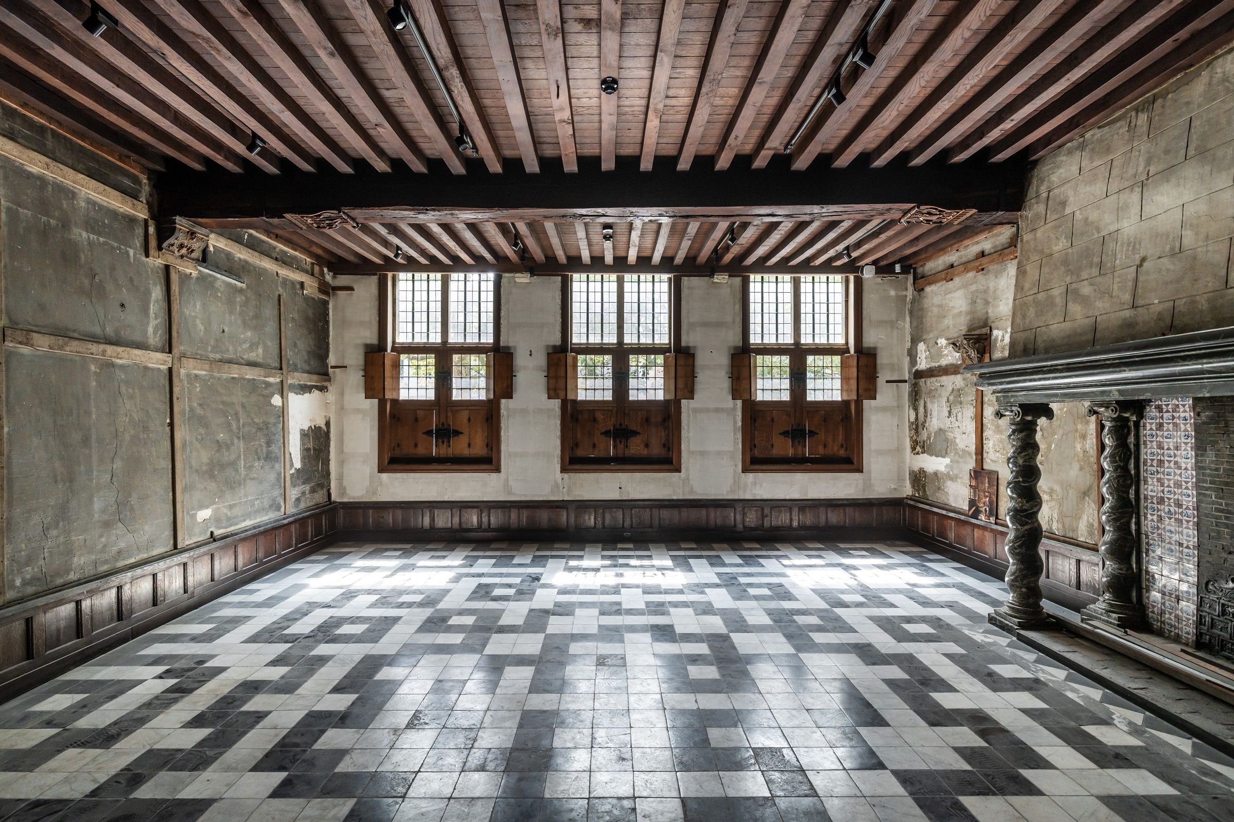 Raadzaal van het Brouwershuis met zwart-witte tegels in geometrisch patroon op de vloer en een houten plafond