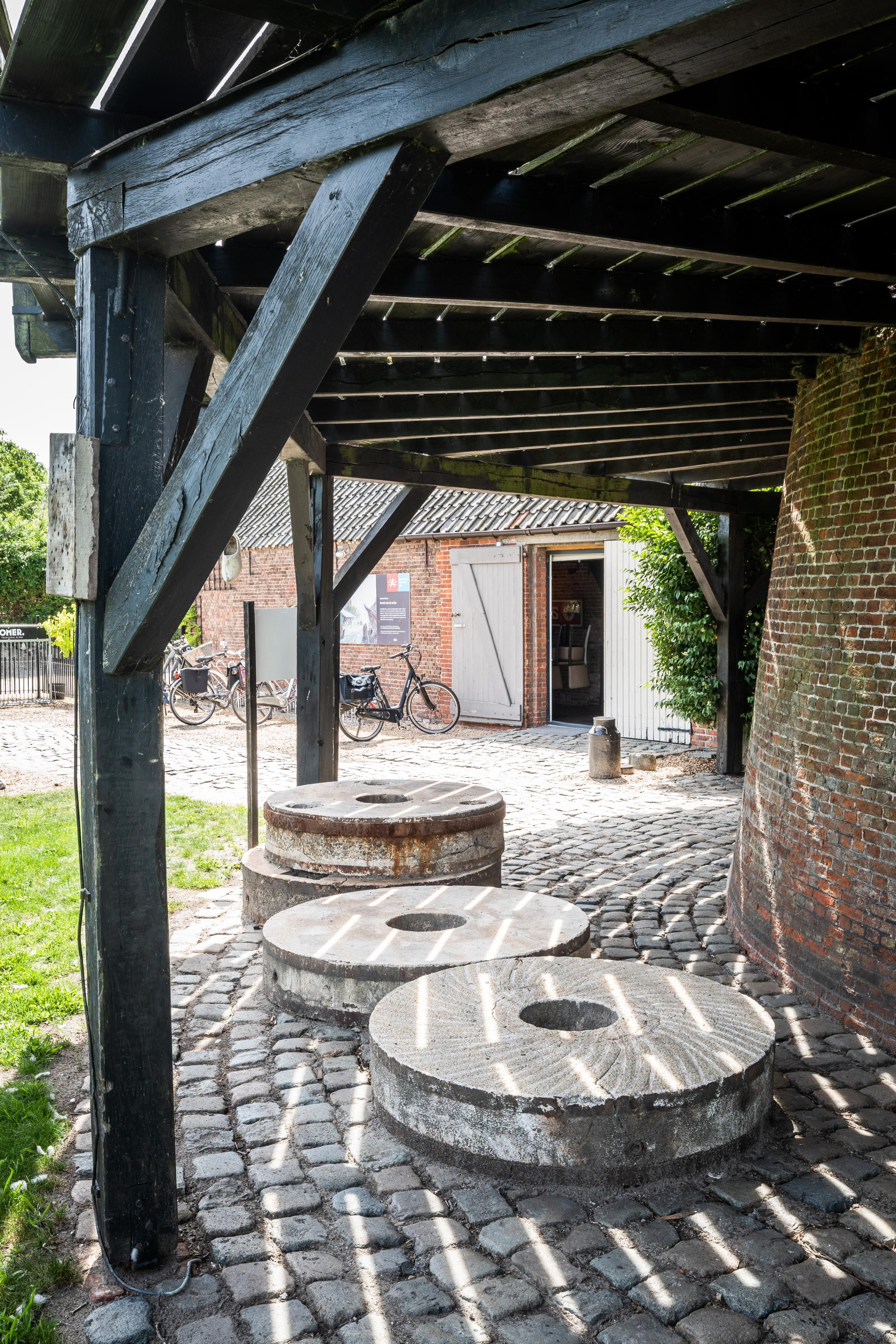 Onder de galerij van de molen liggen vier molenstenen.