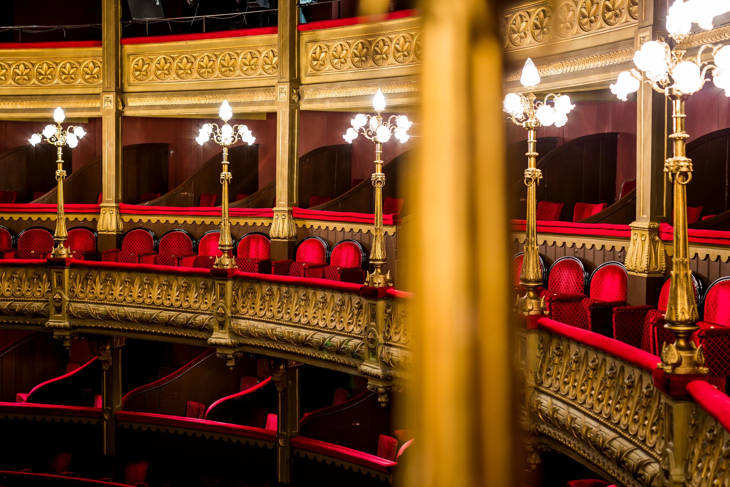 Interieur van de theaterzaal met rode fluwelen stoelen en gouden details