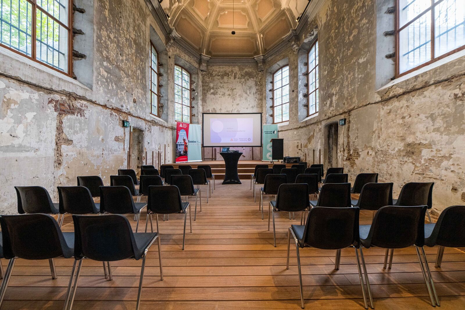 De binnenkant van de kerk, met zwarte stoelen en een scherm vooraan.